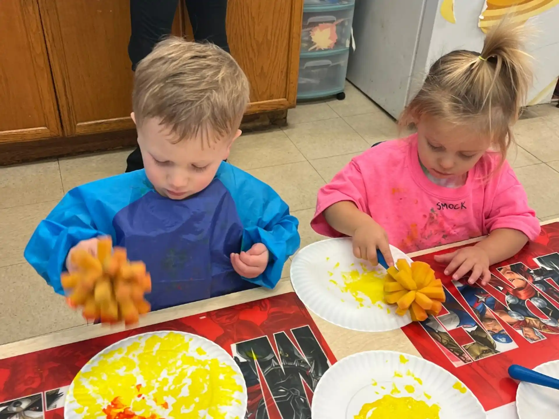 a couple of children sitting at a table with food