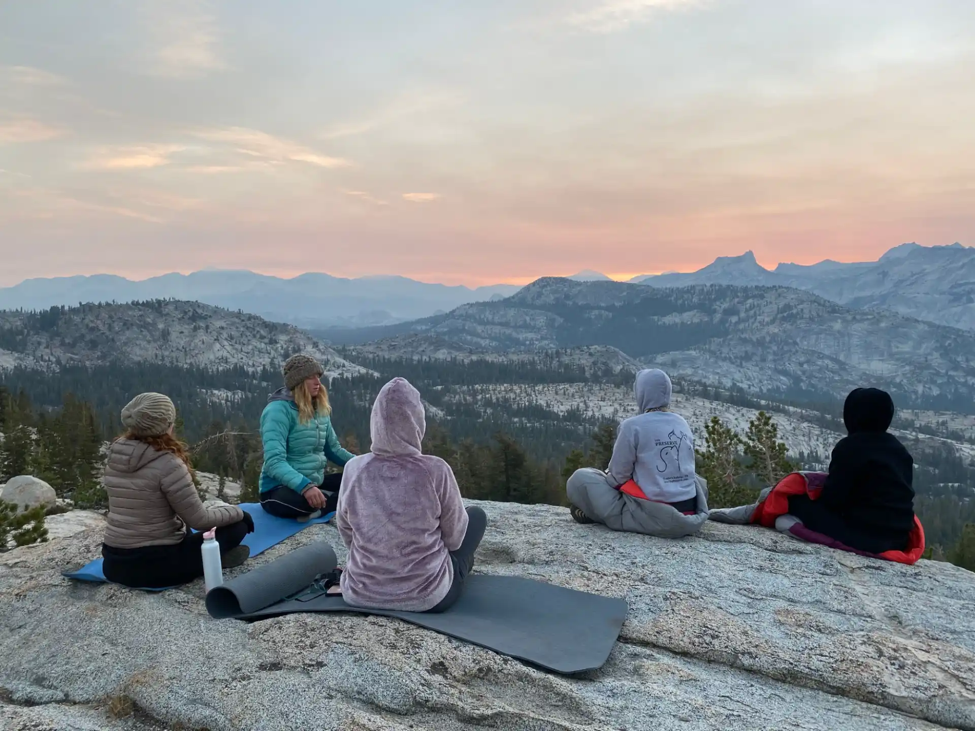 a group of people sitting on a rock overlooking a valley