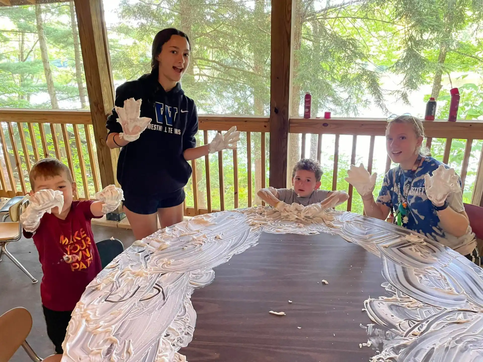 a person and children sitting at a table with a person standing behind them