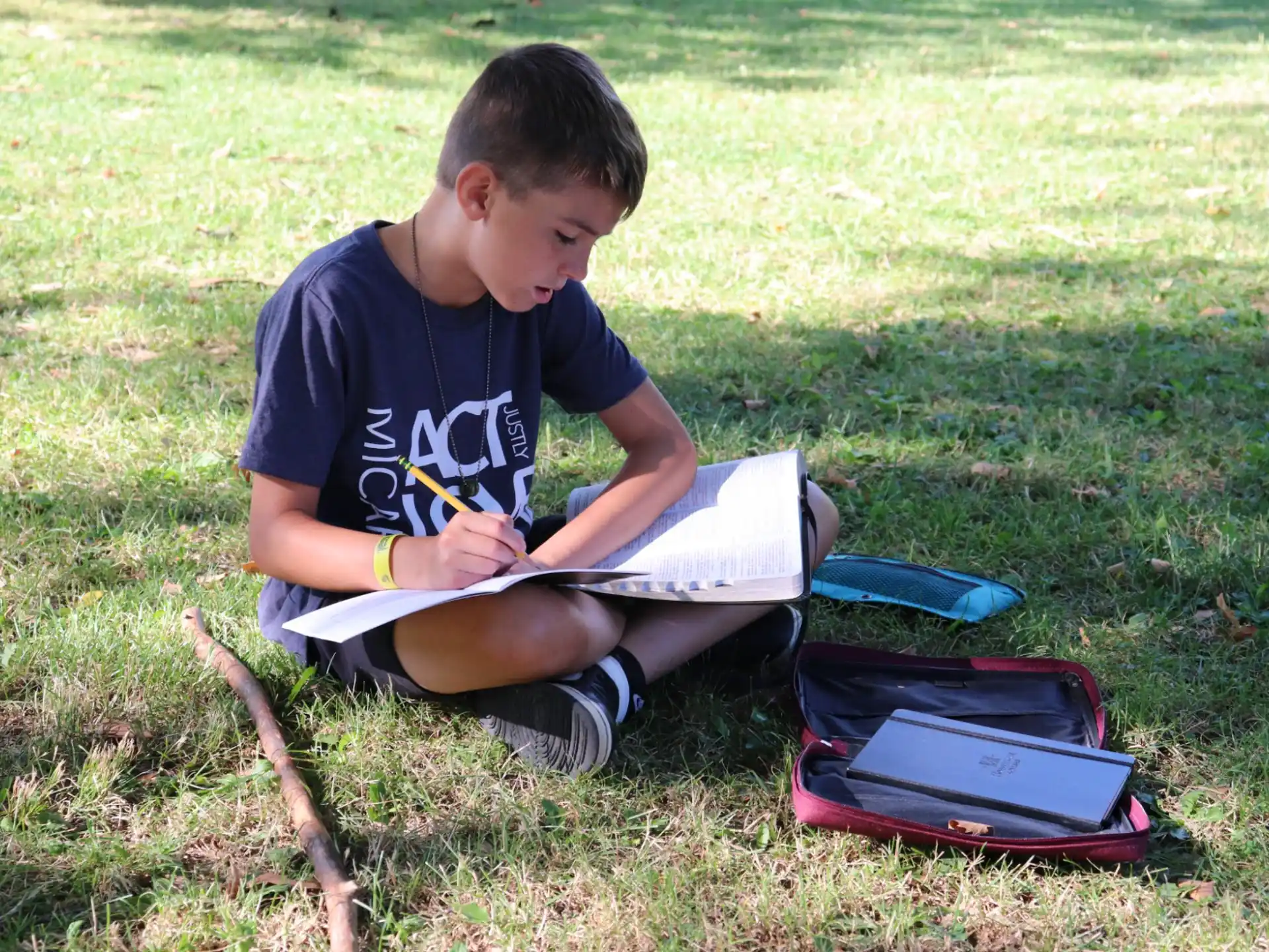 a boy sitting on the grass reading a book