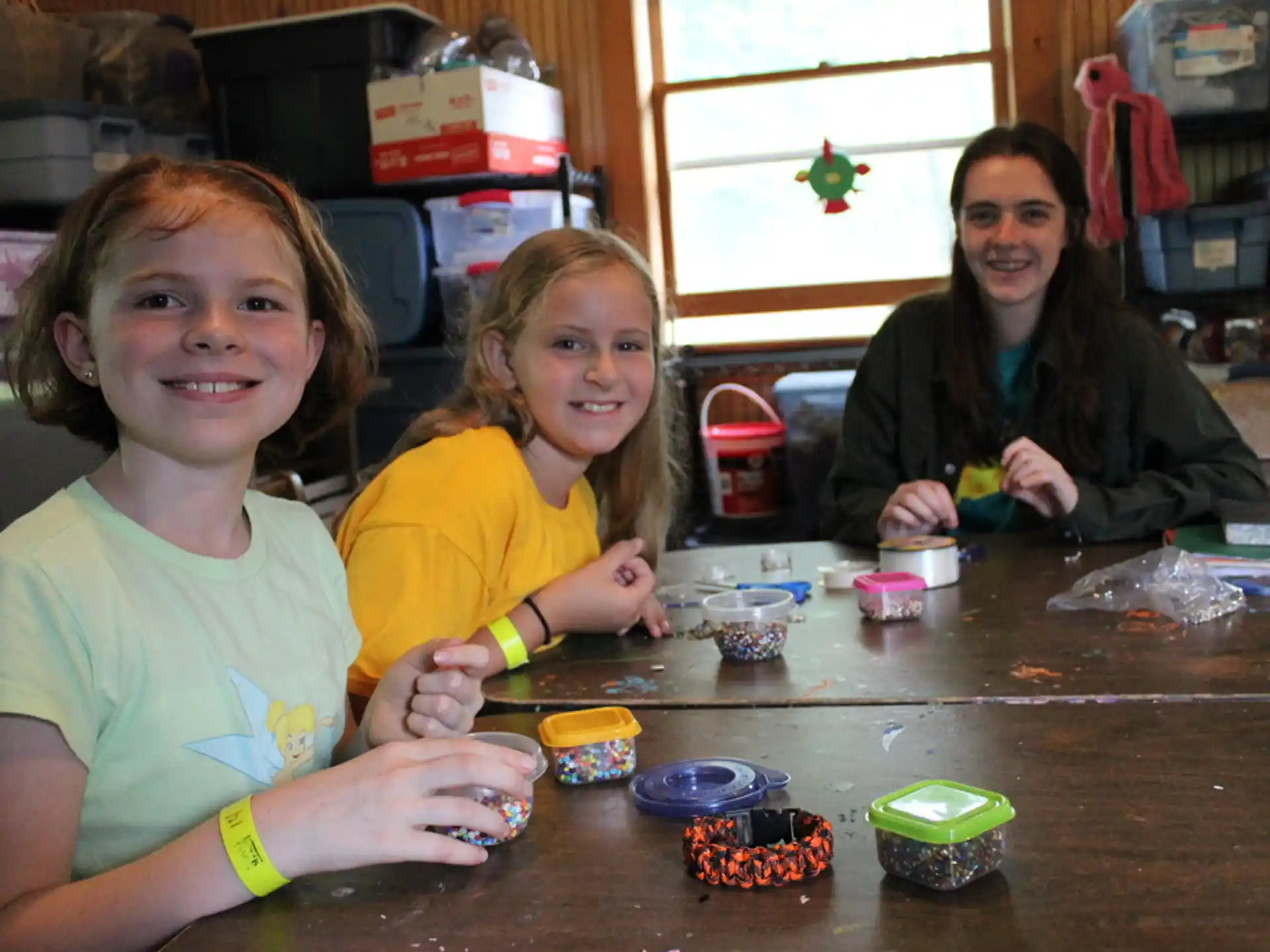 a group of children sitting at a table with small cups of food