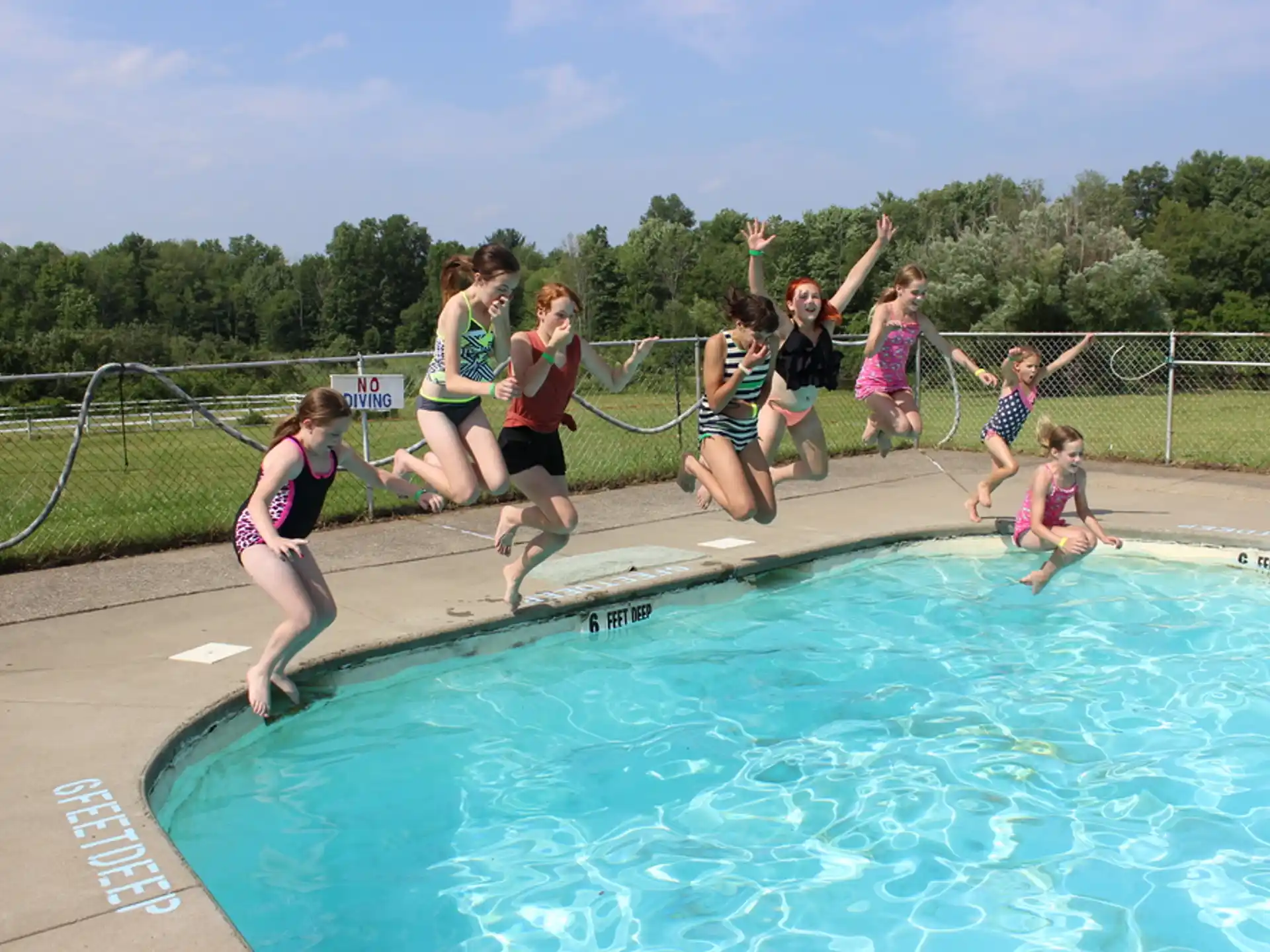 a group of people jumping into a pool
