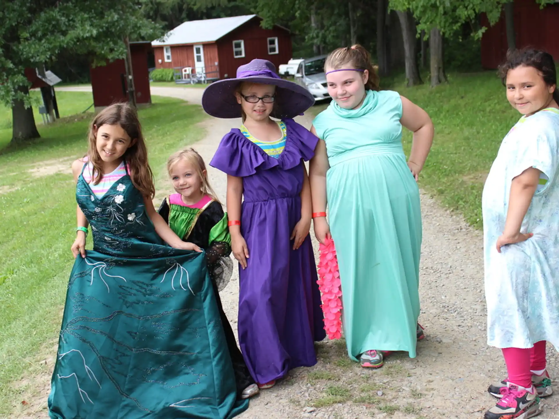 a group of women in dresses and hats posing for a photo