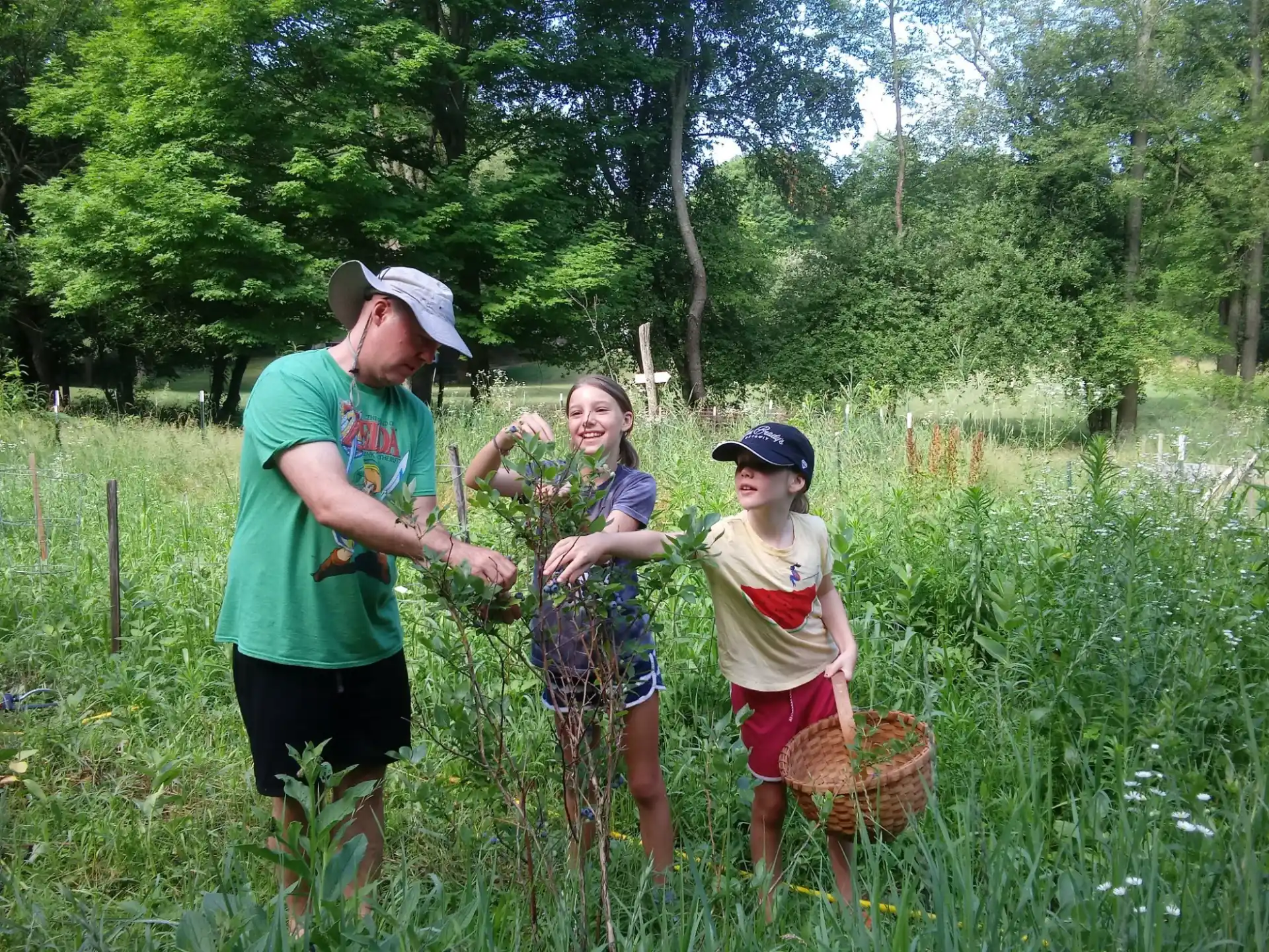 a group of people standing in a field with a basket of plants
