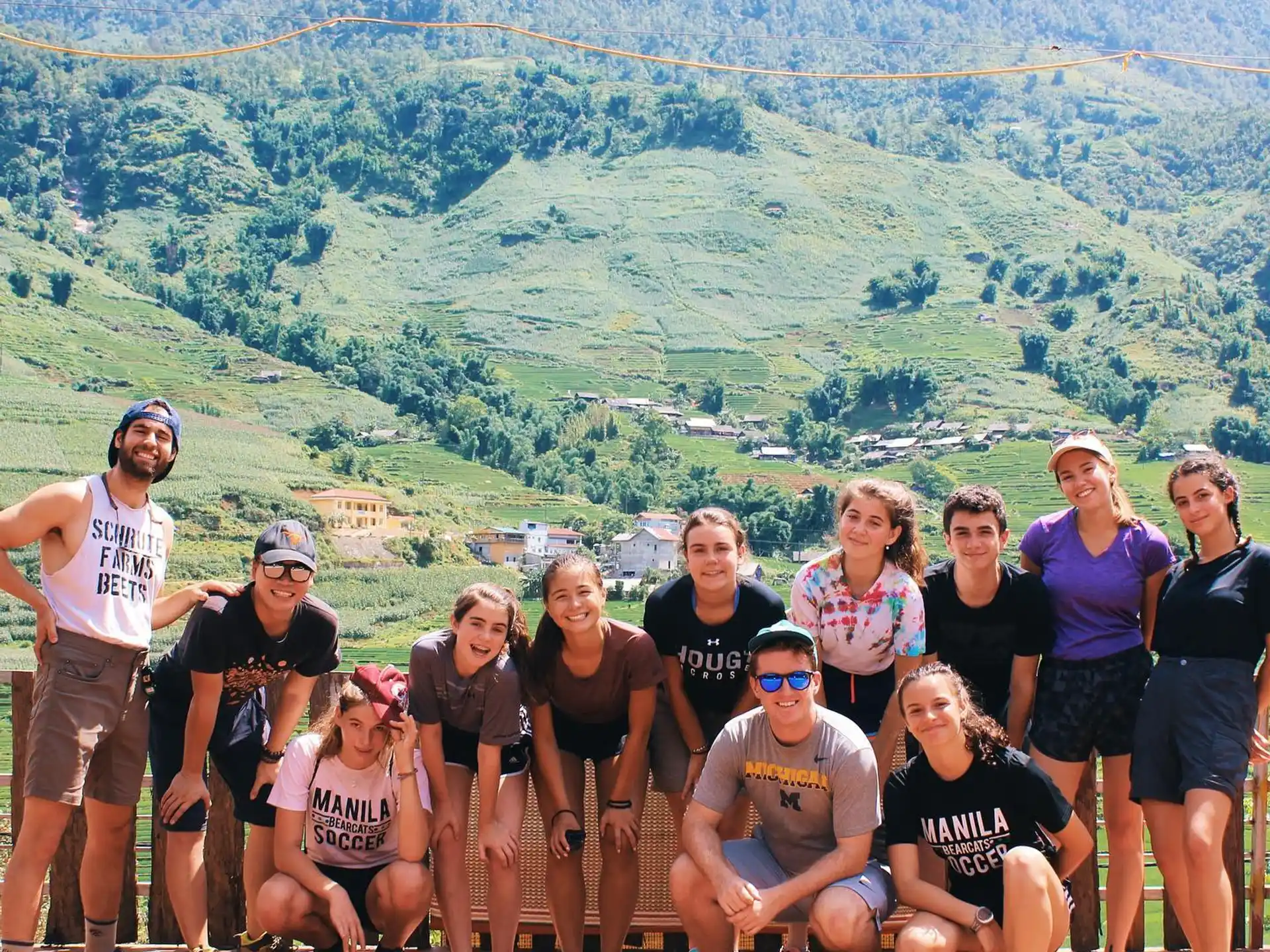 a group of people posing for a photo in front of a green mountain