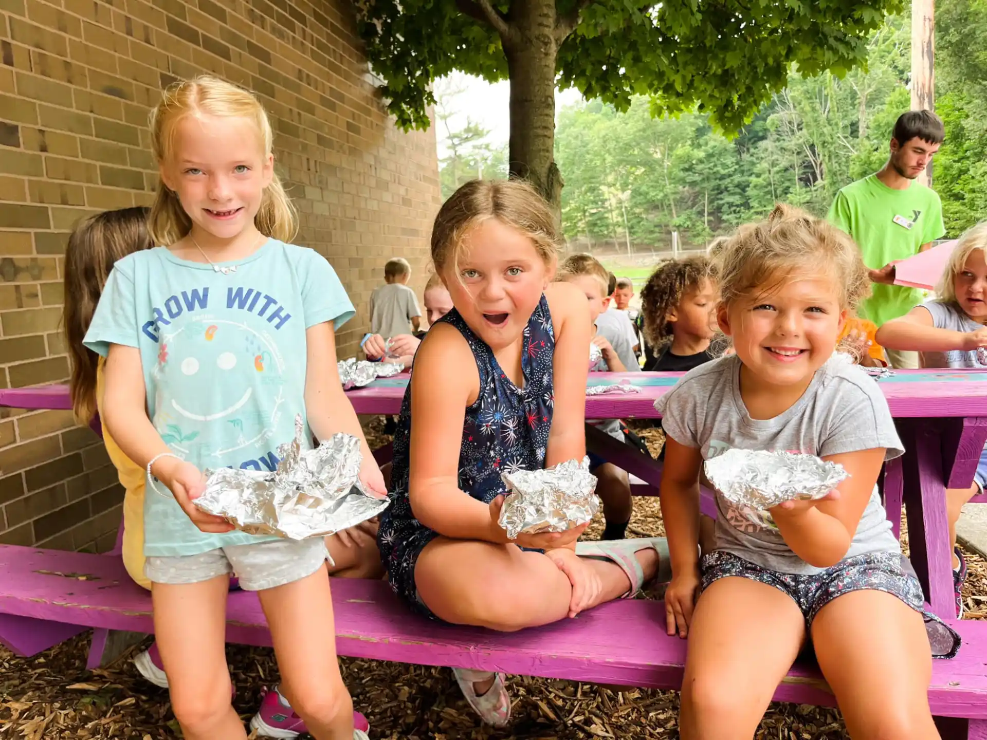 a group of children sitting on a bench with food in their hands