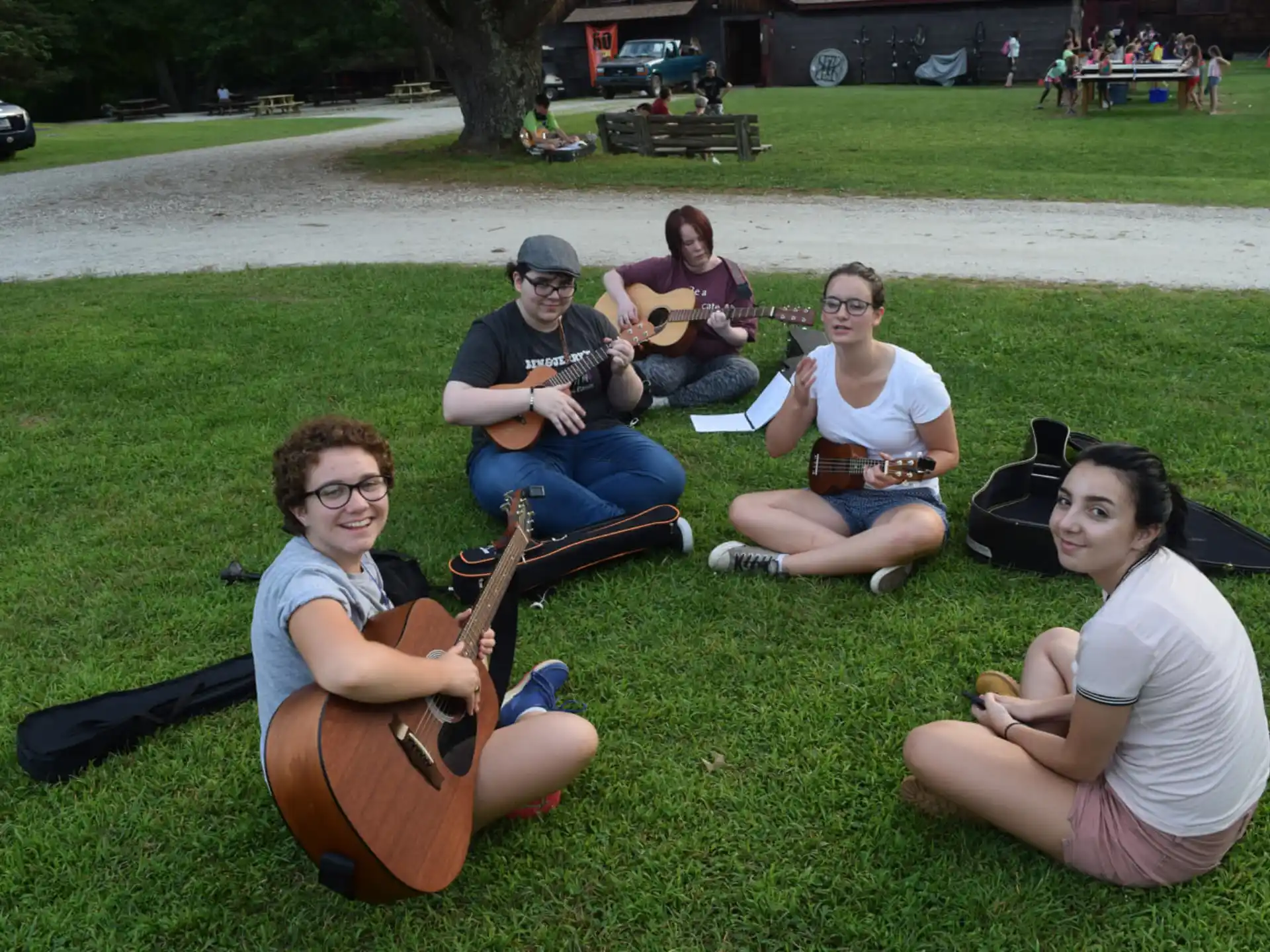 a group of people sitting on the grass playing instruments