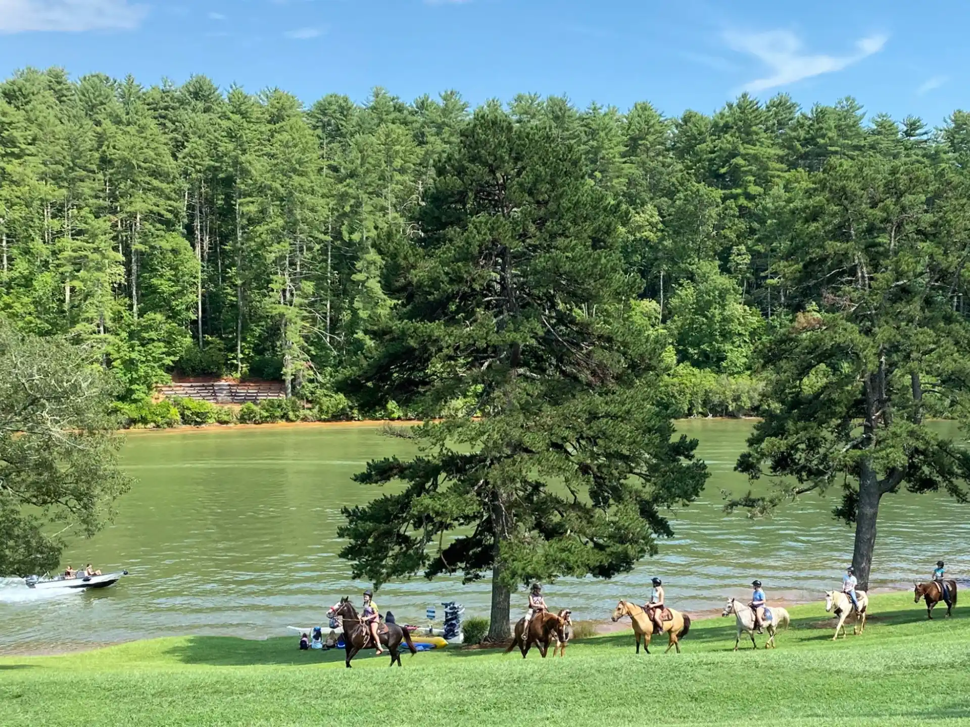 a group of people riding horses by a river