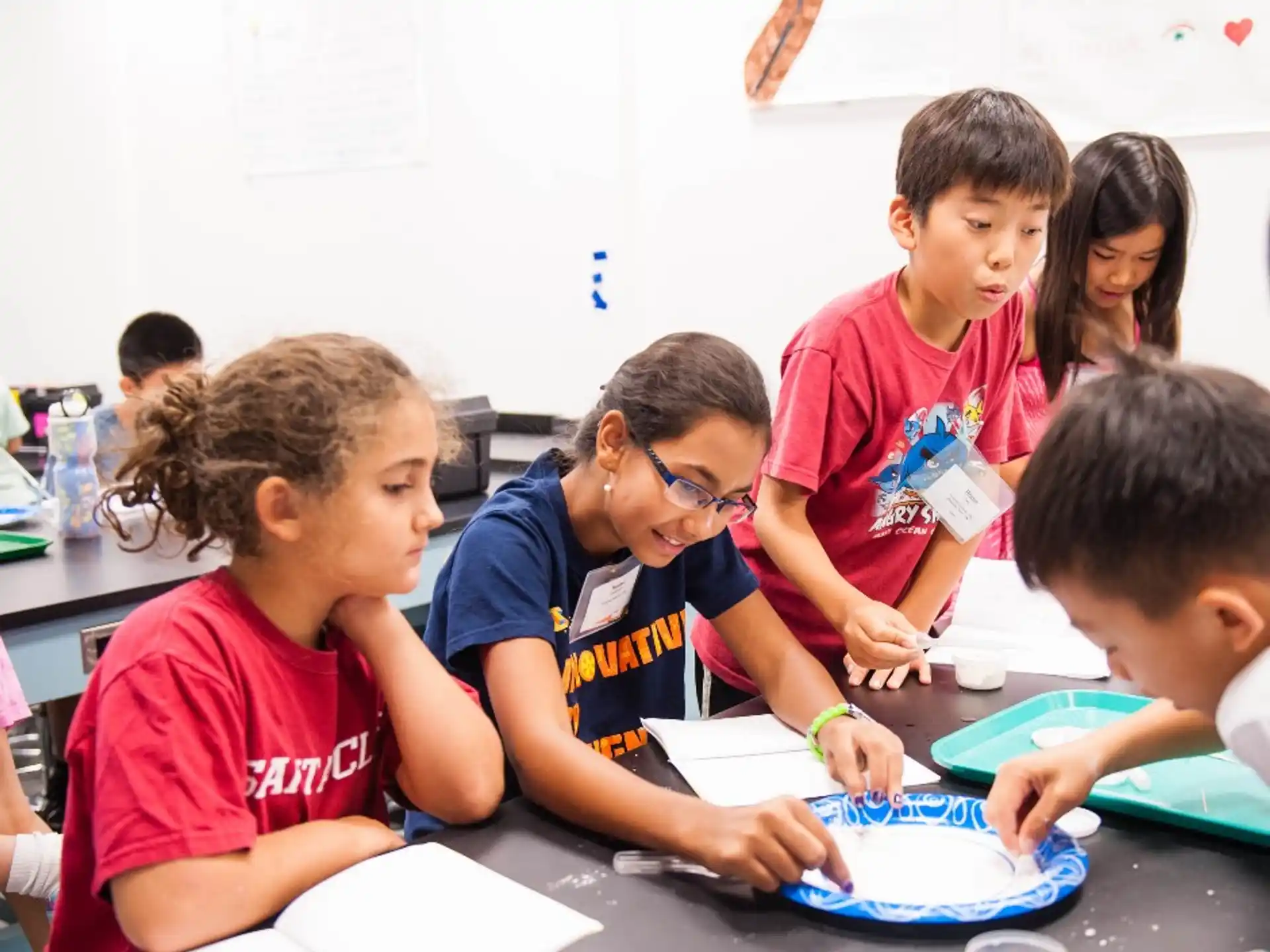 a group of children sitting at a table writing on paper
