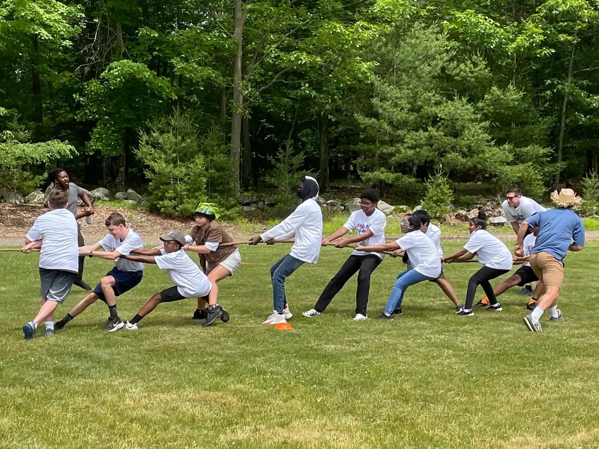 a group of people playing tug of war in a field