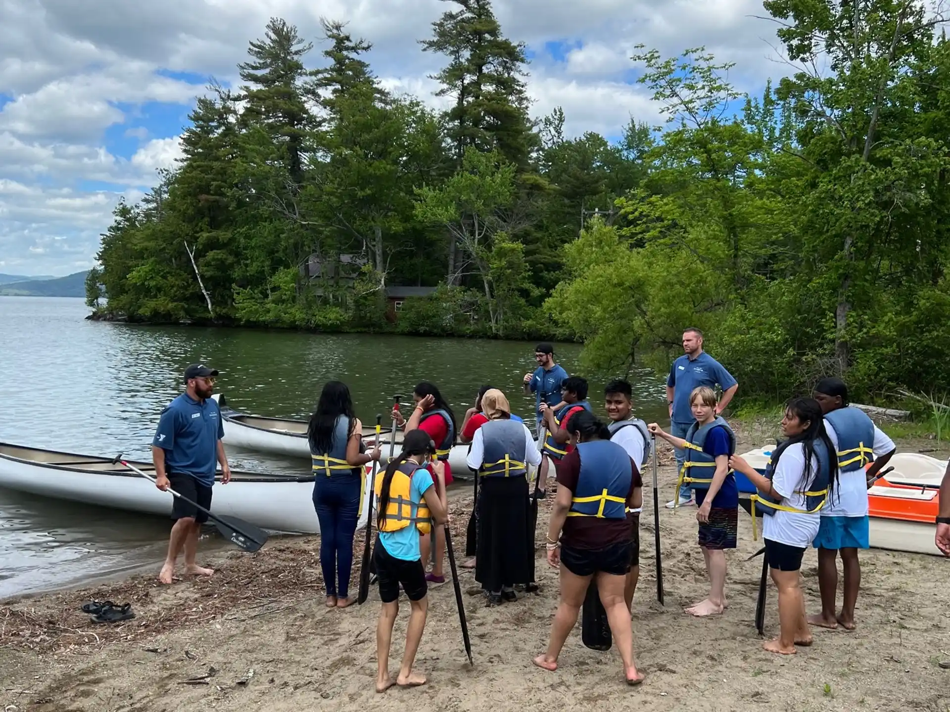 a group of people standing on a beach with boats in the water