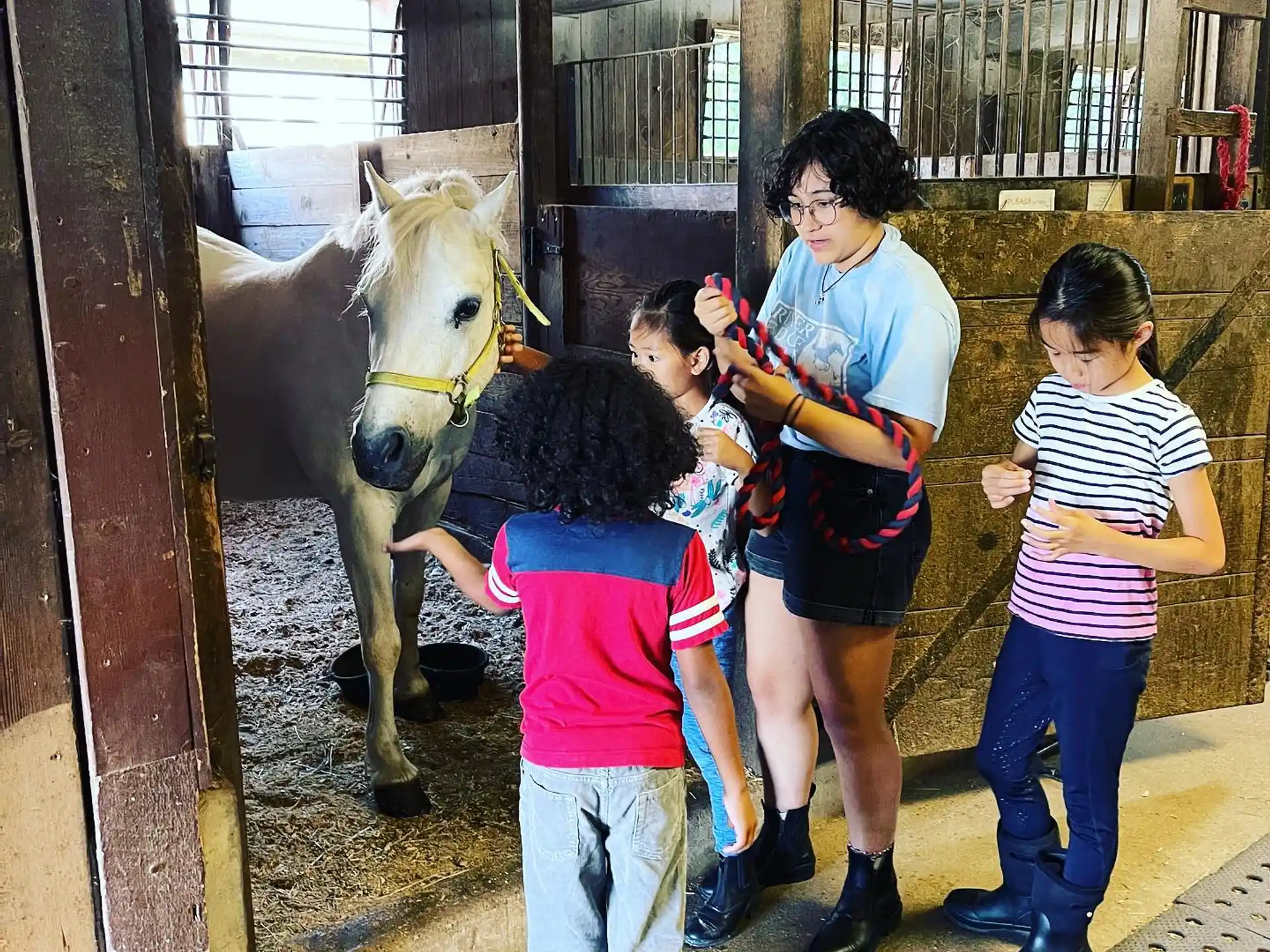 a group of people standing next to a horse in a stable