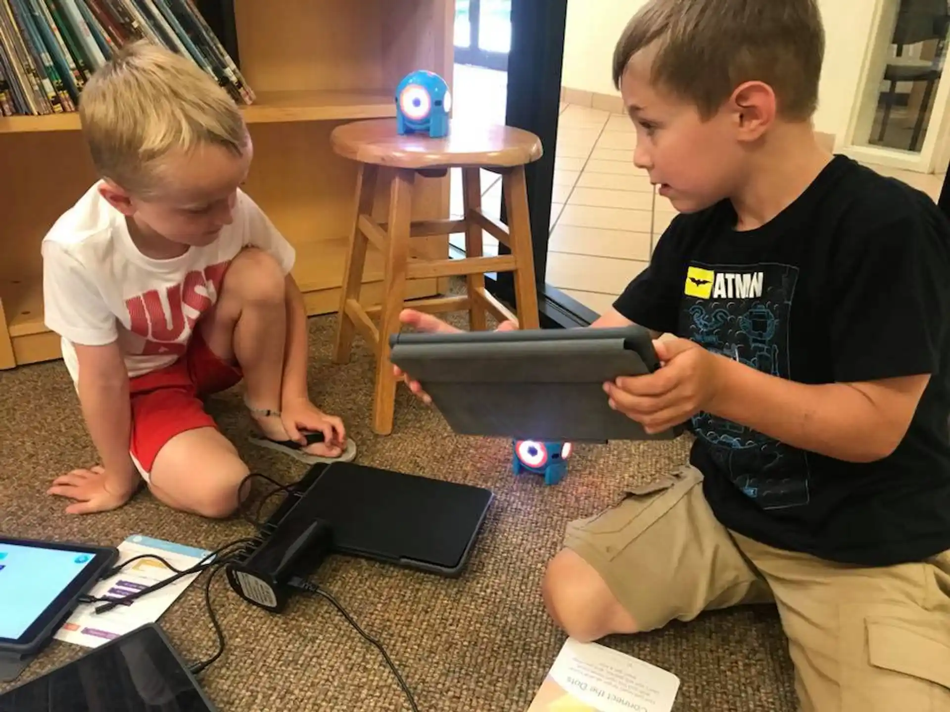 a couple of boys sitting on the floor looking at a laptop