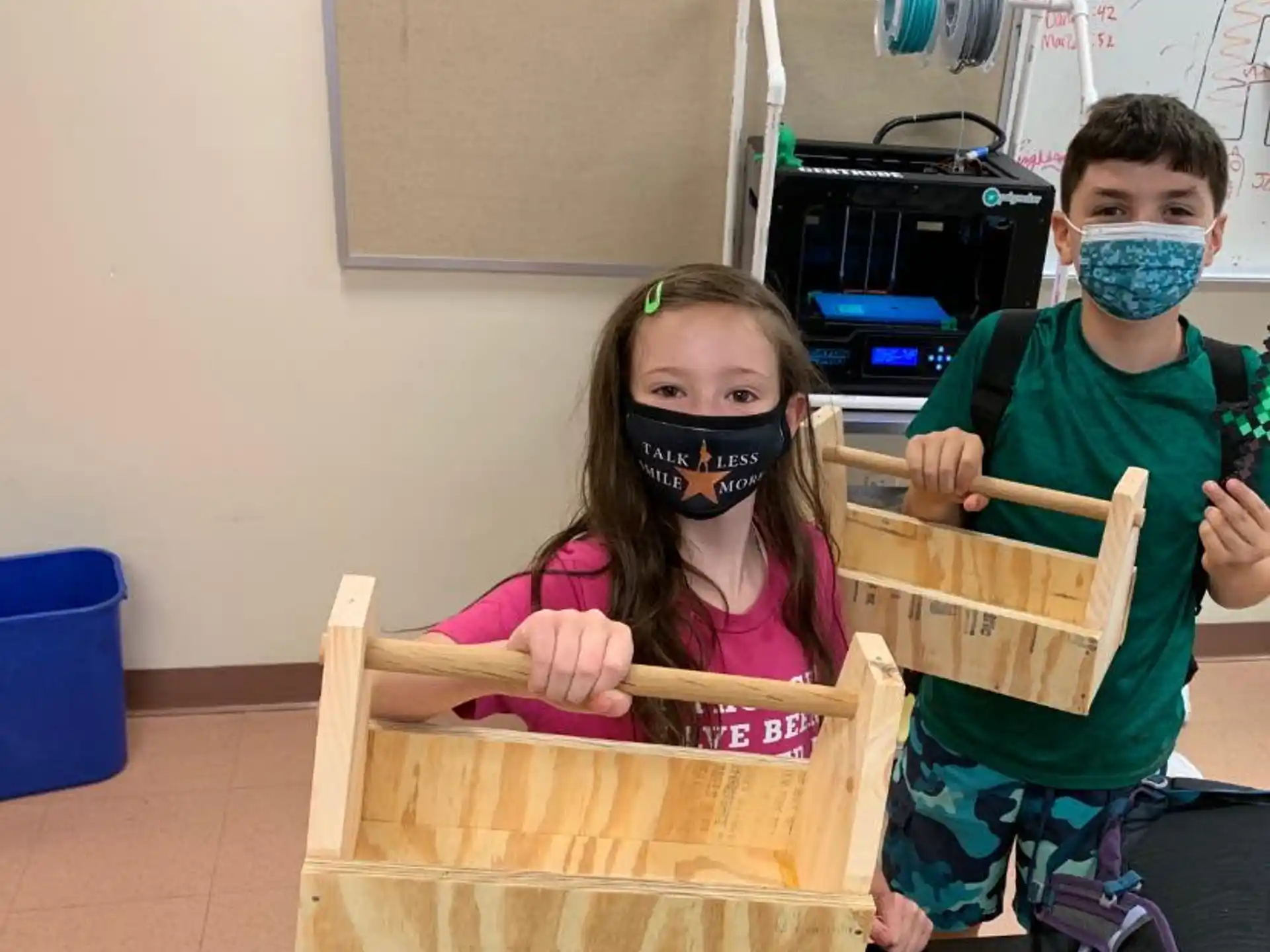 a group of kids wearing masks and holding a box