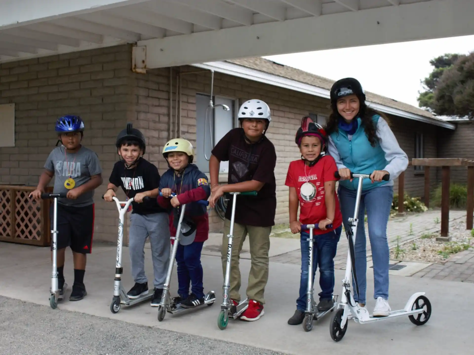 a group of people wearing helmets and holding scooters