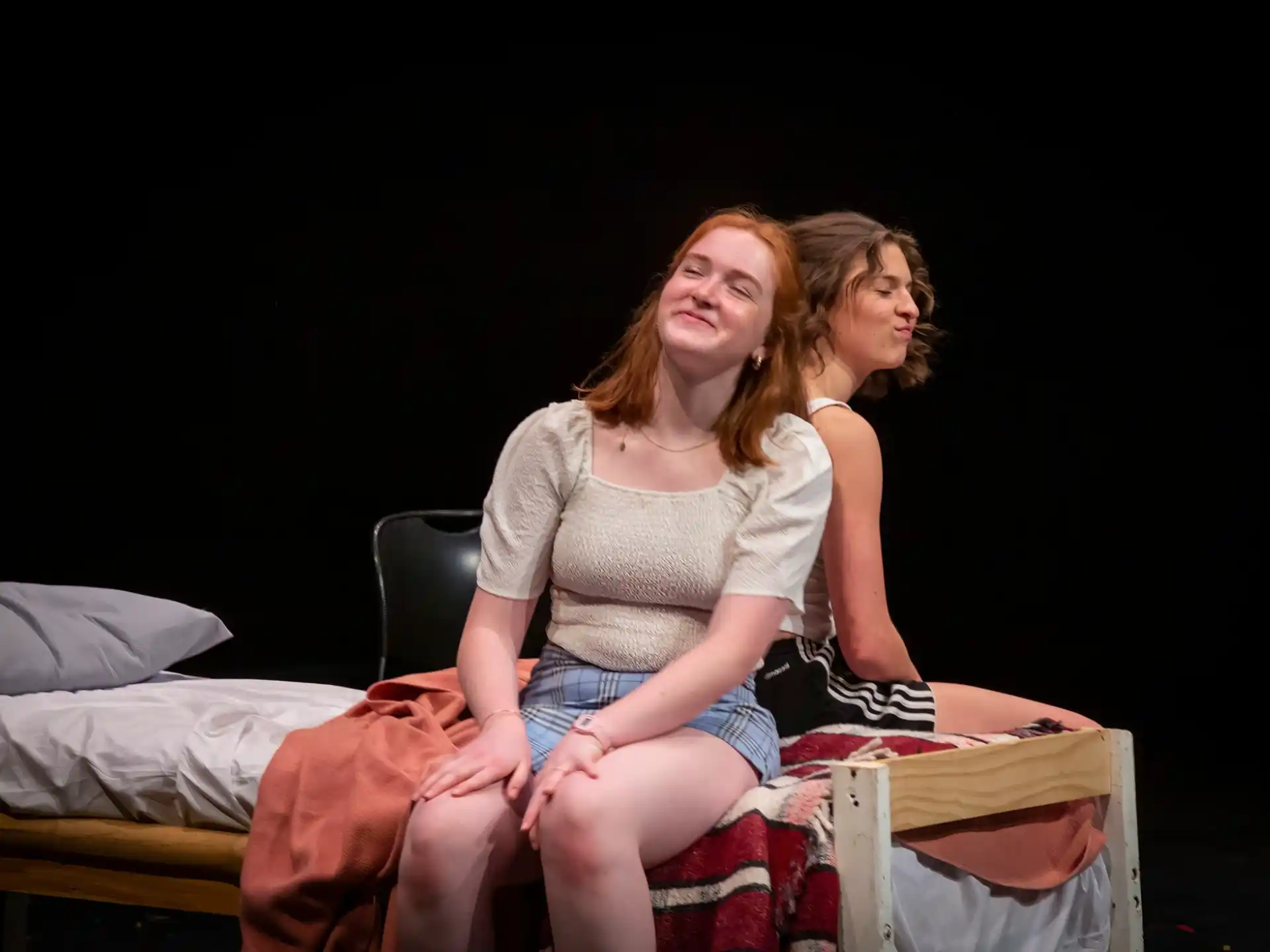 a couple of women sitting on a bed
