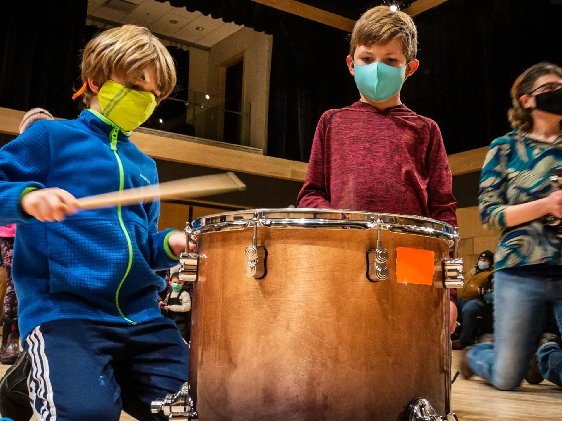 a group of kids wearing face masks and playing drums