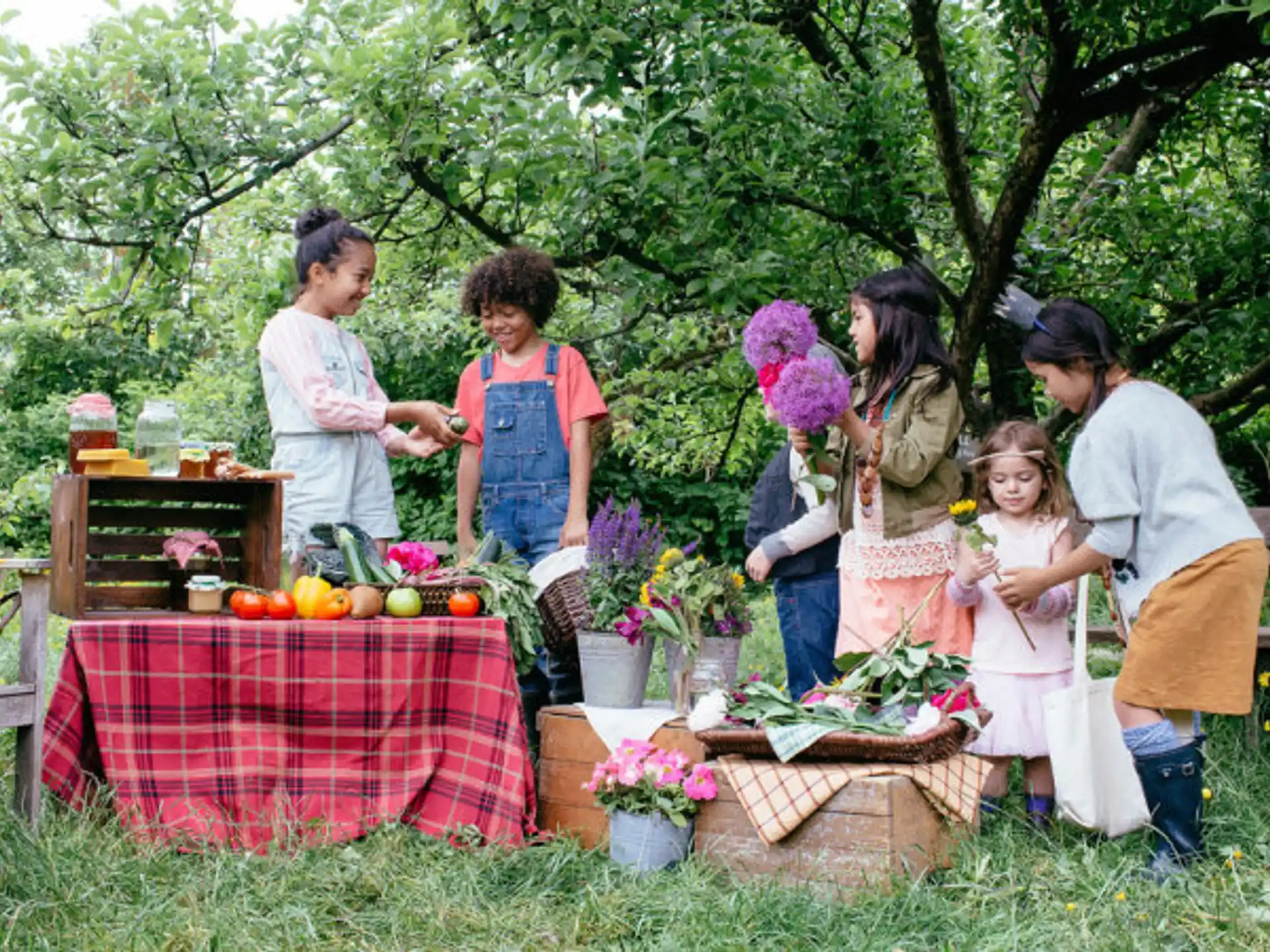 a group of people standing around a table with flowers and fruit