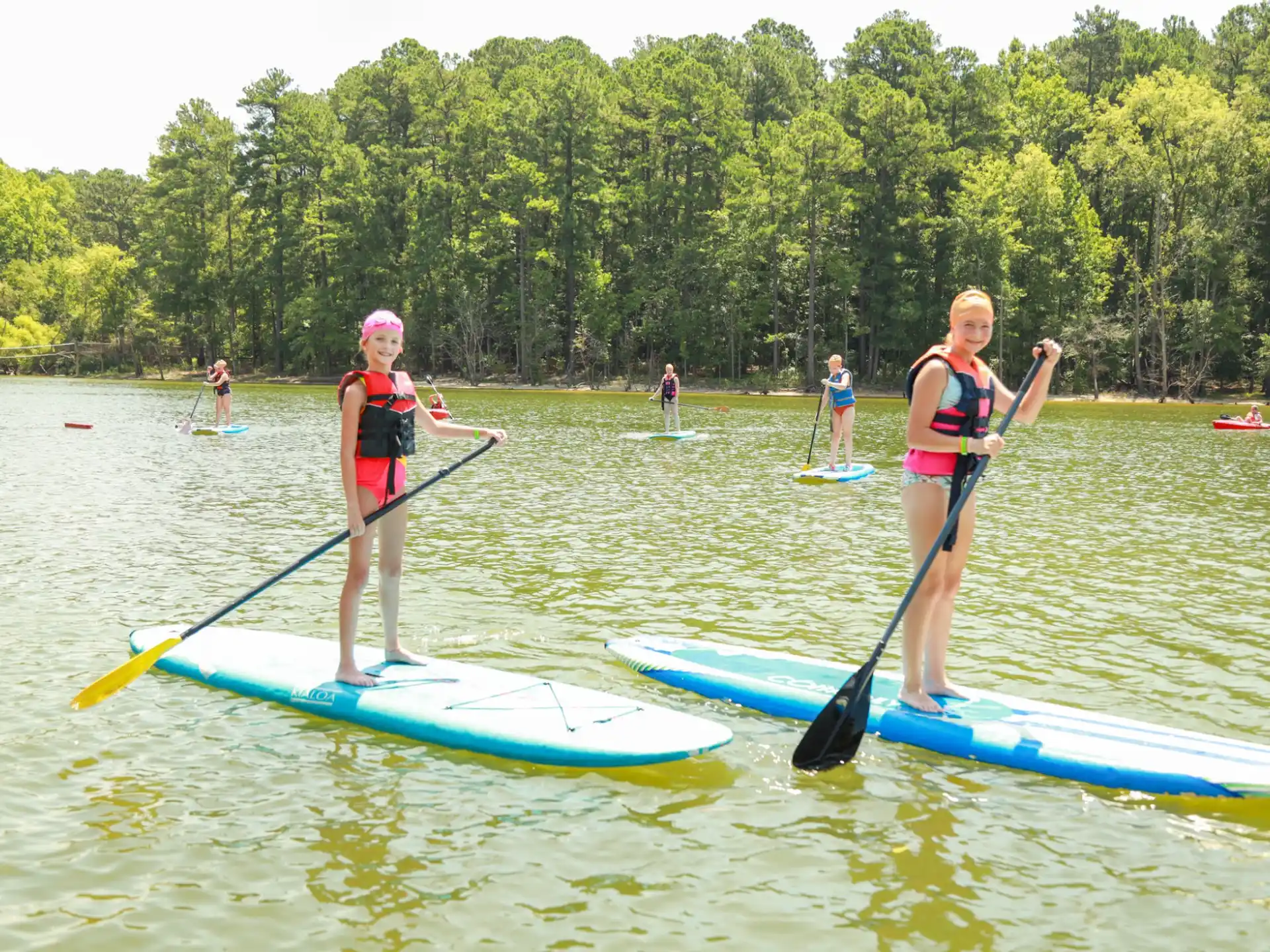 a couple of girls on paddle boards in a lake