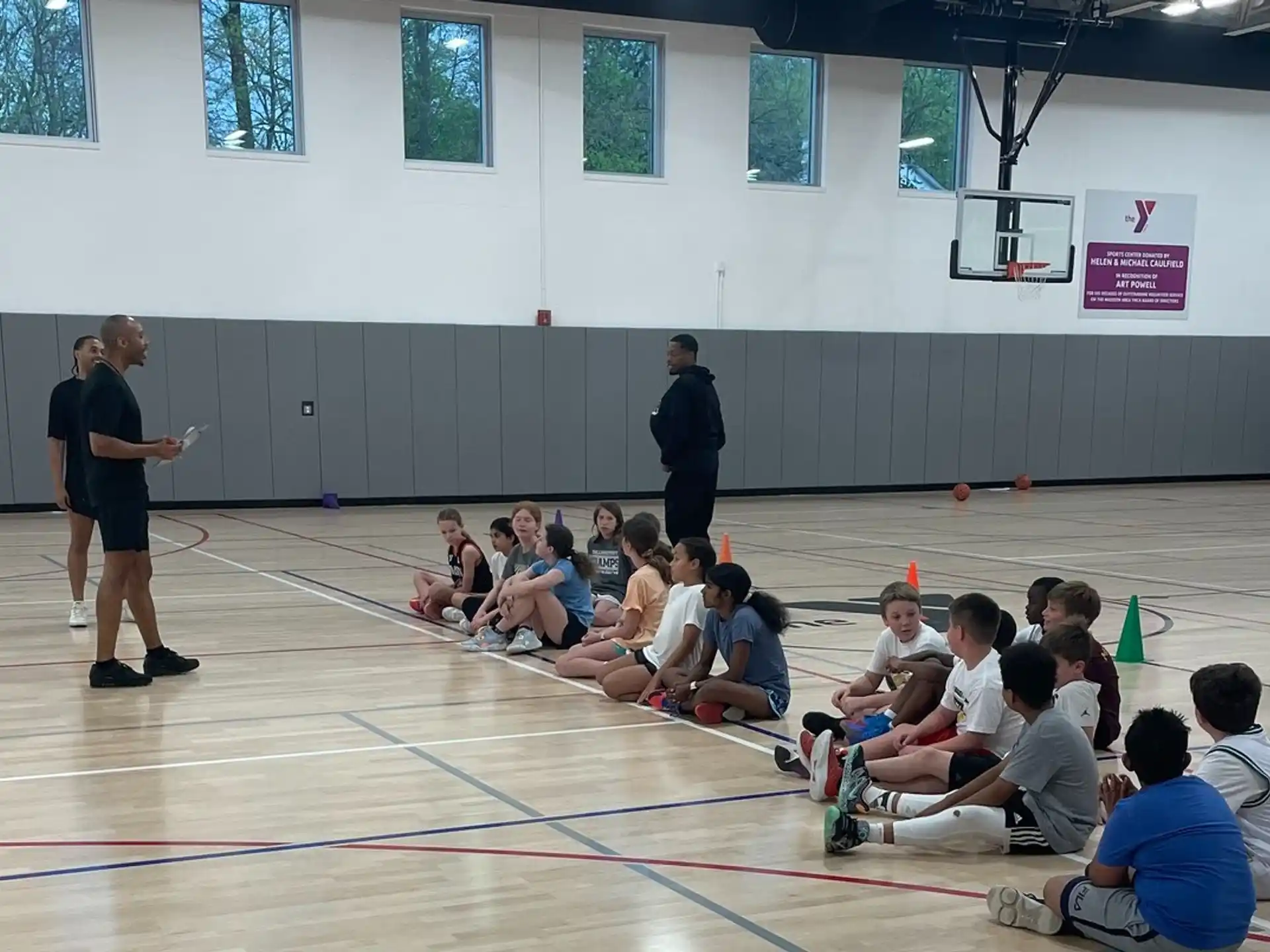 a group of people sitting on the floor in a gym