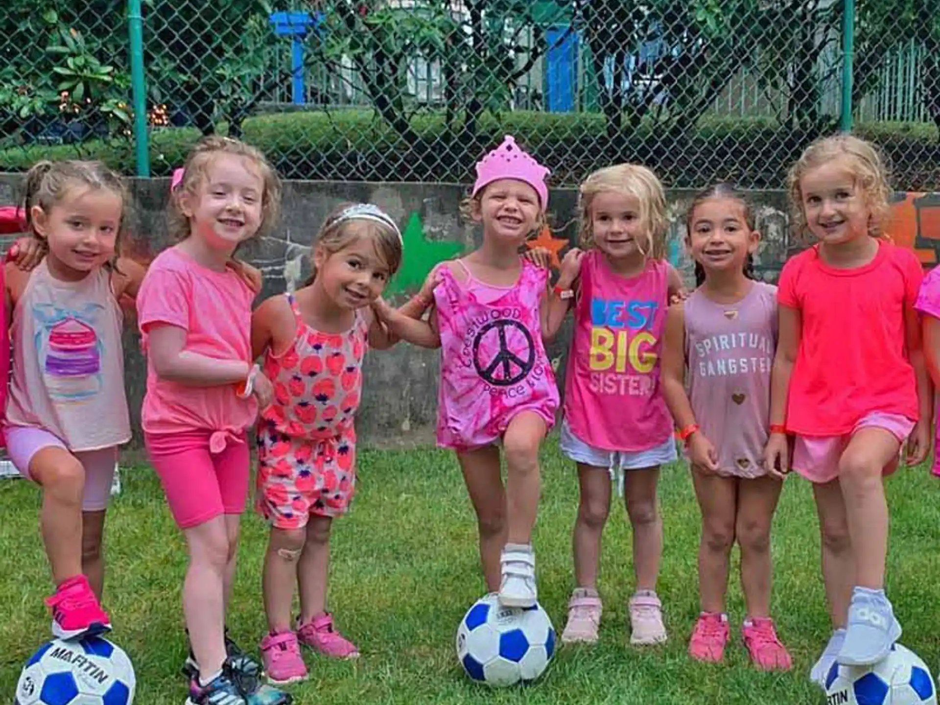 a group of girls posing for a picture with football balls