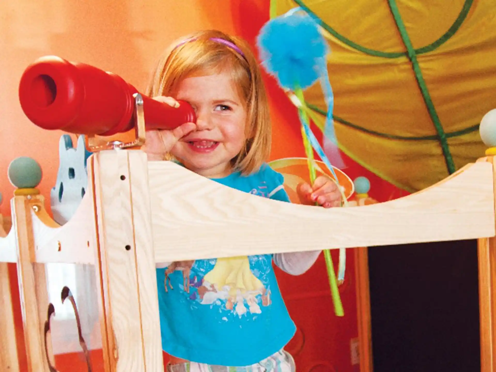 a young girl holding a red blow dryer