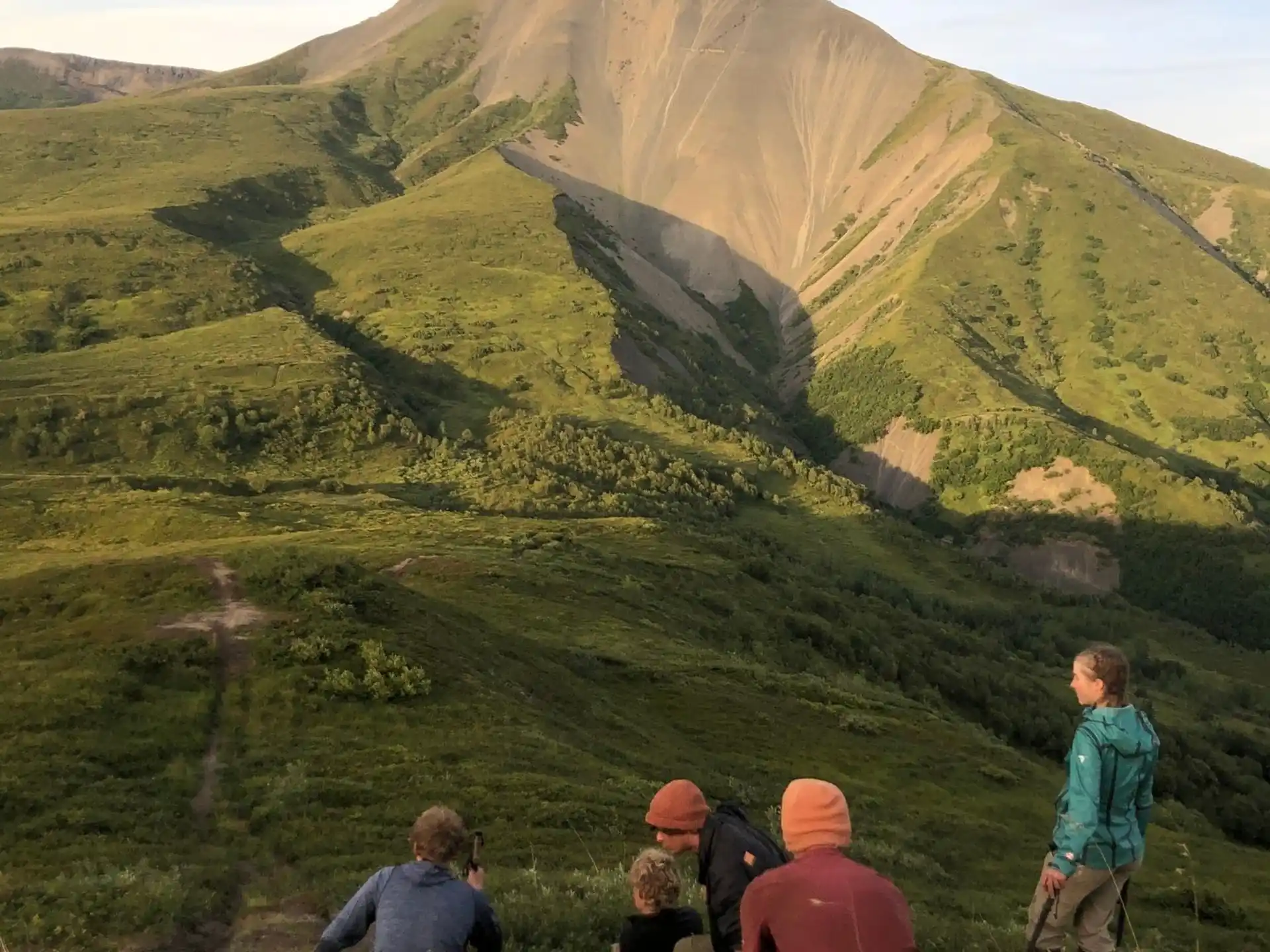 a group of people on a grassy hill with a valley below
