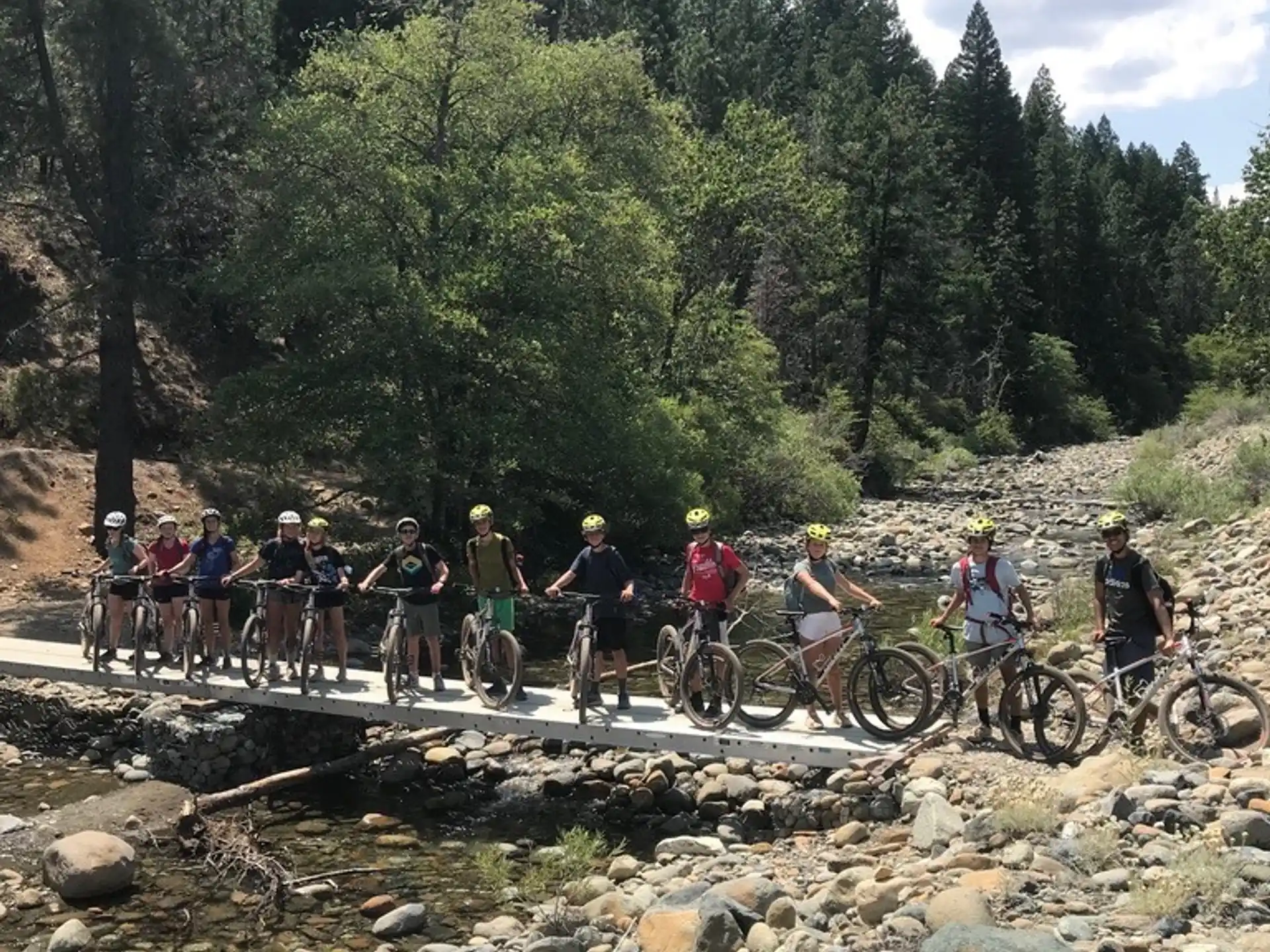 a group of people with bicycles on a rocky river bed