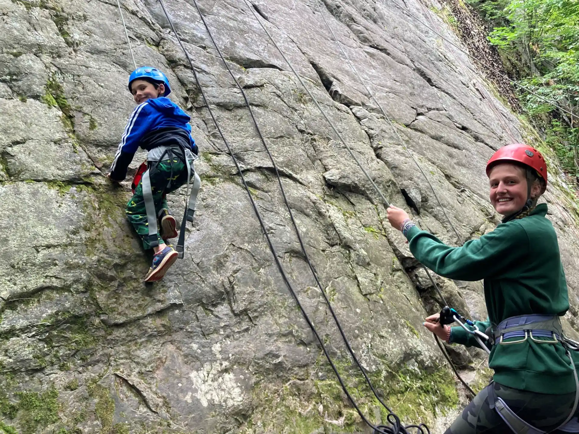 a couple of people climbing a rock wall