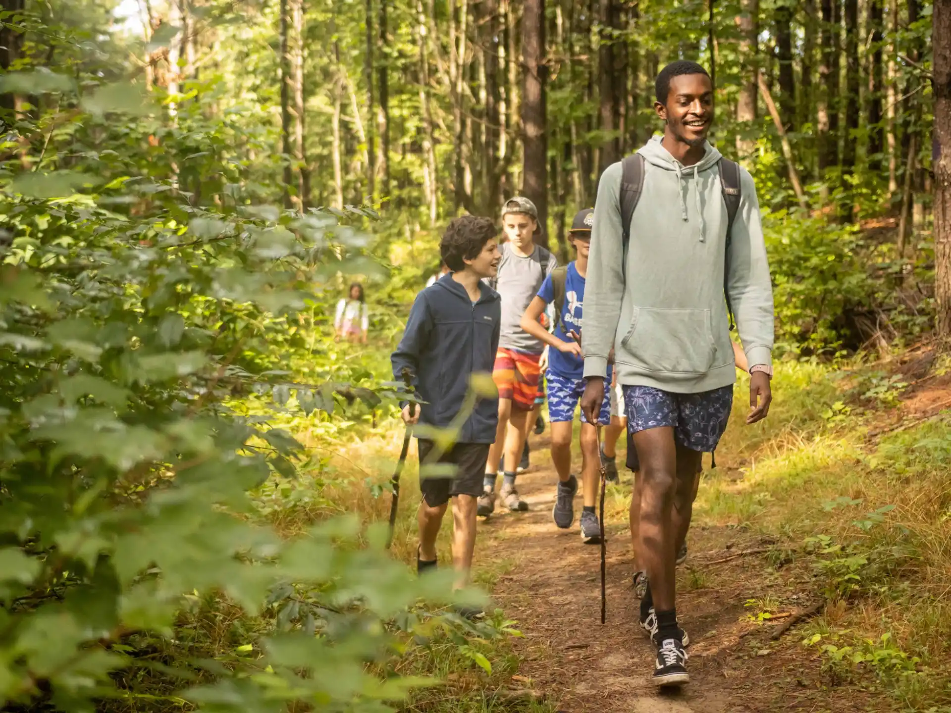 a group of people walking on a trail in the woods