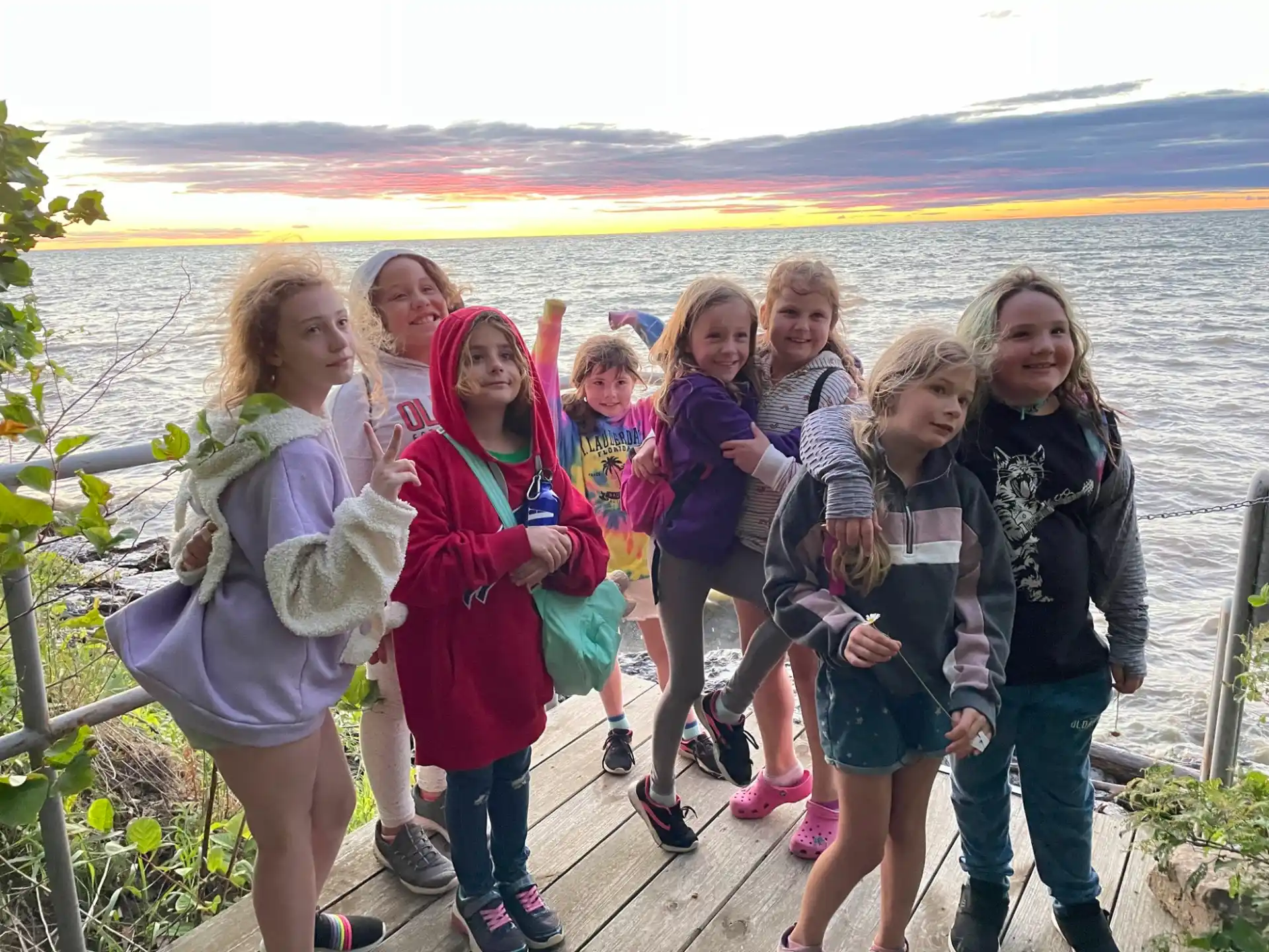 a group of girls posing for a picture next to a body of water