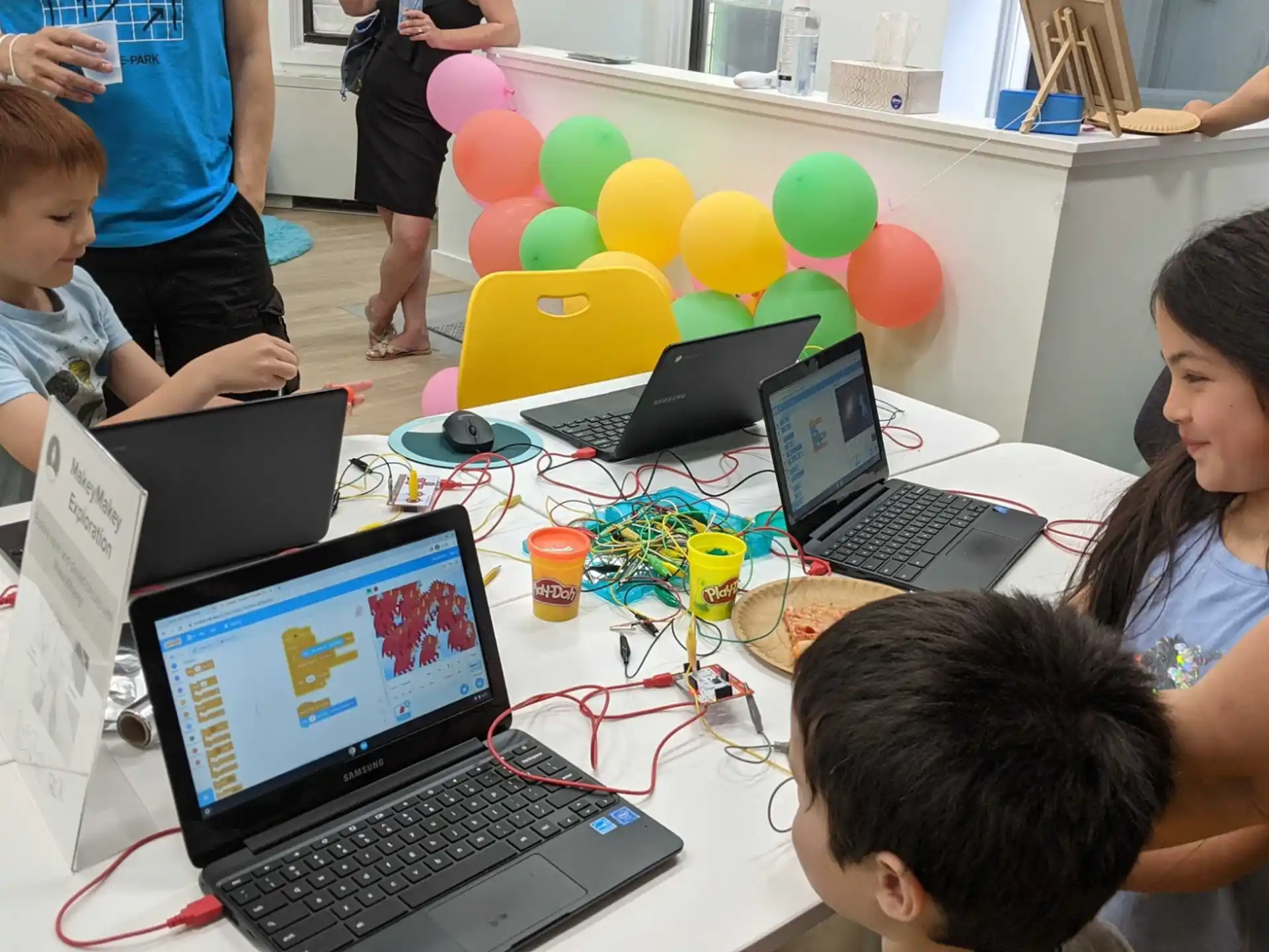 a group of people sitting around a table with laptops