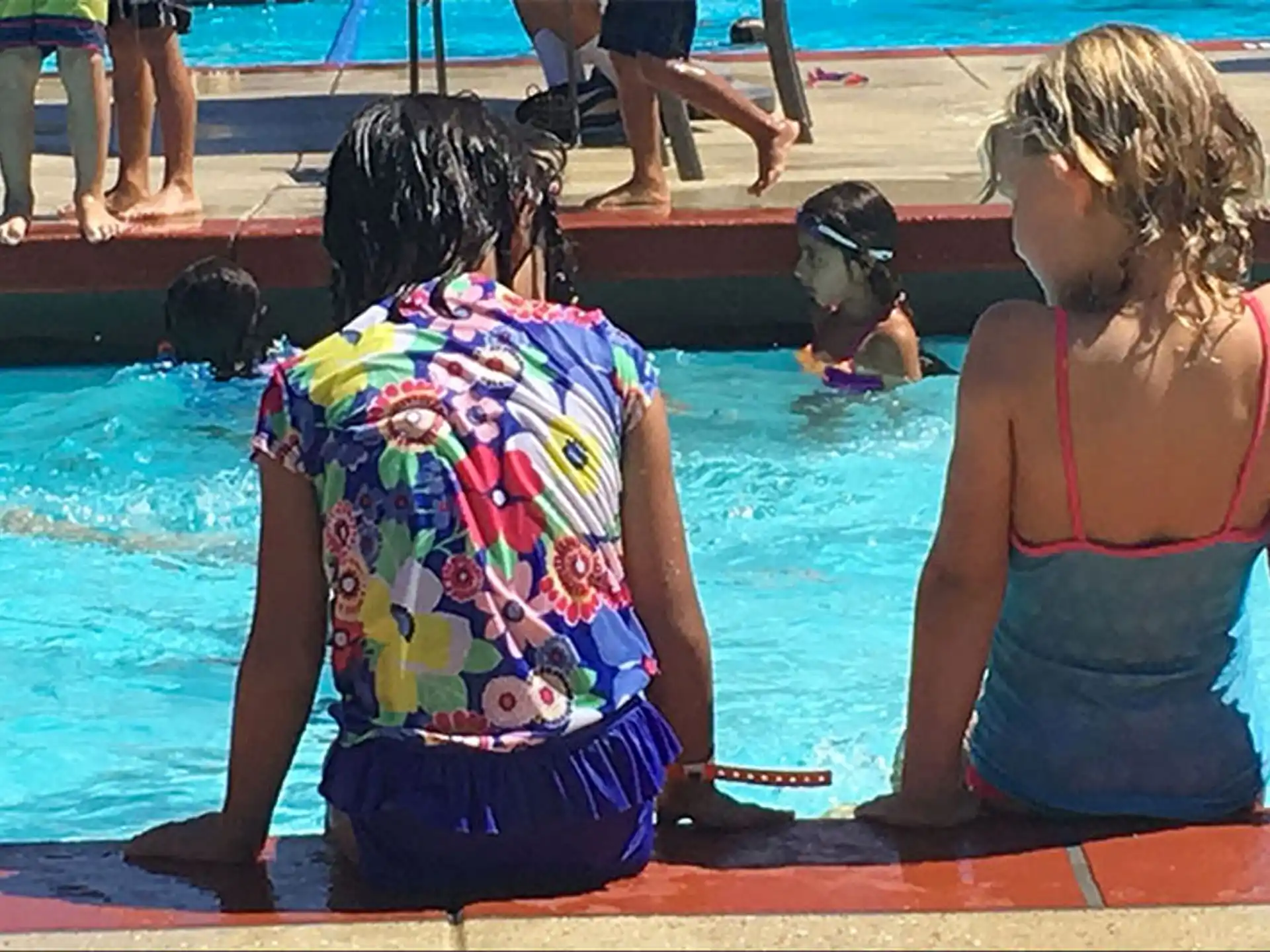 a group of women sitting on a bench by a pool