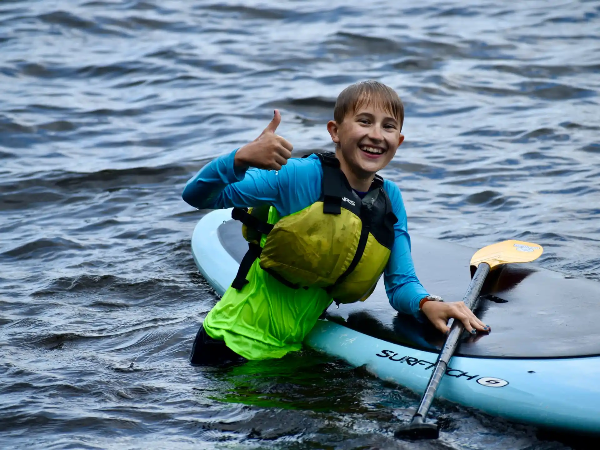 a boy in a life jacket on a raft in the water
