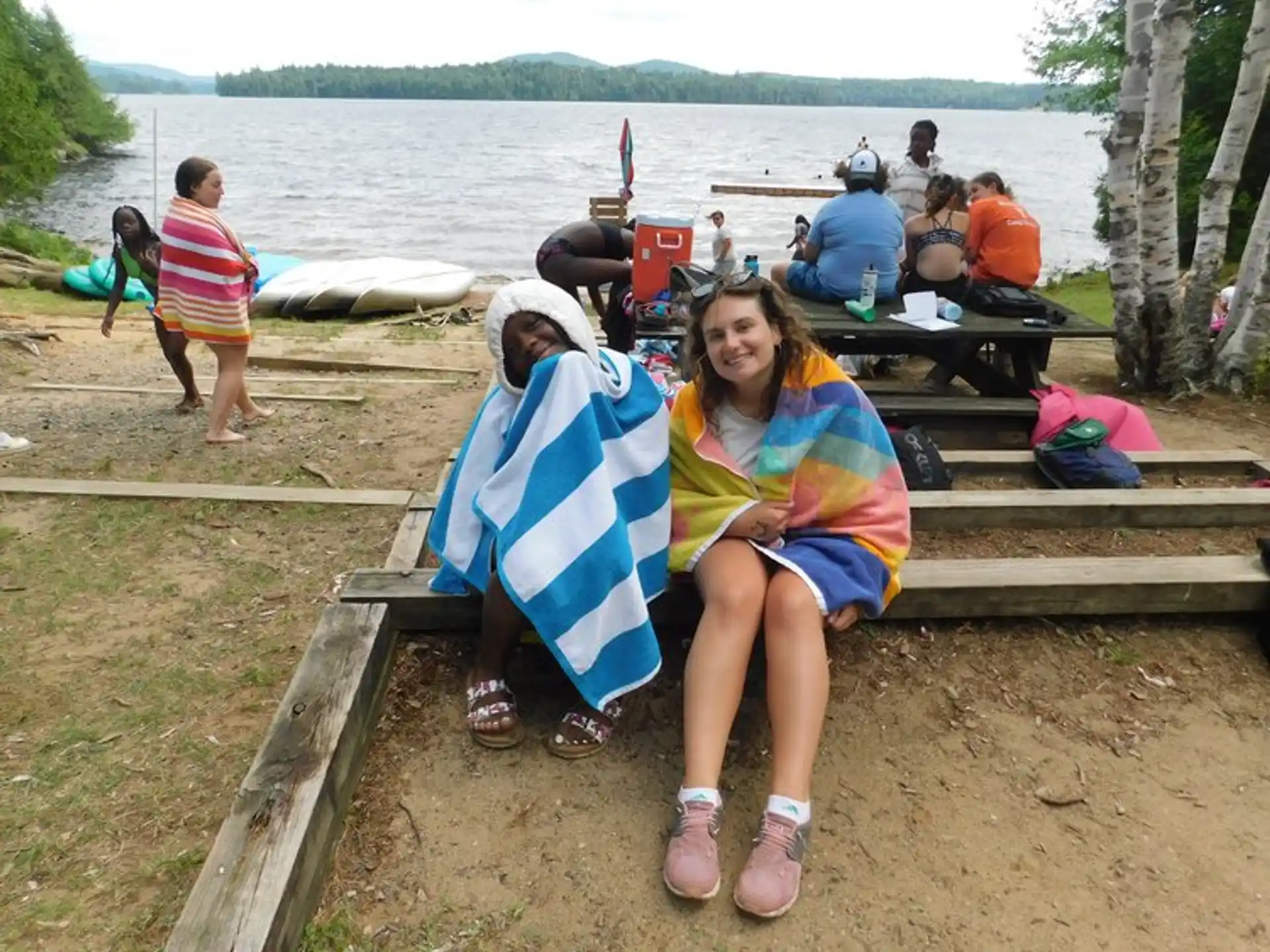a couple of women sitting on a bench by a body of water
