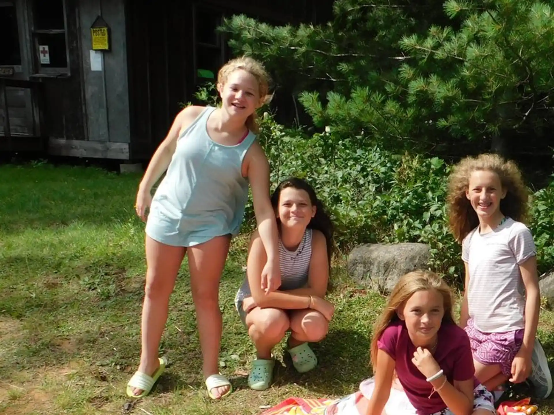 a group of girls sitting on a blanket in a yard