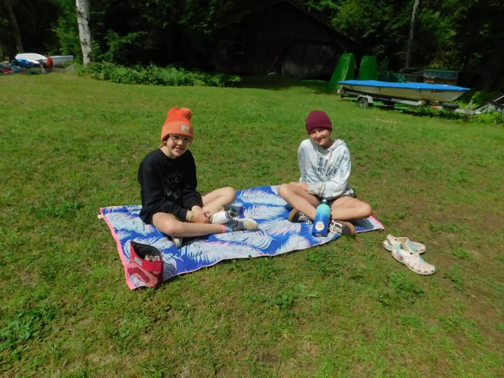 two boys sitting on a blanket in the grass