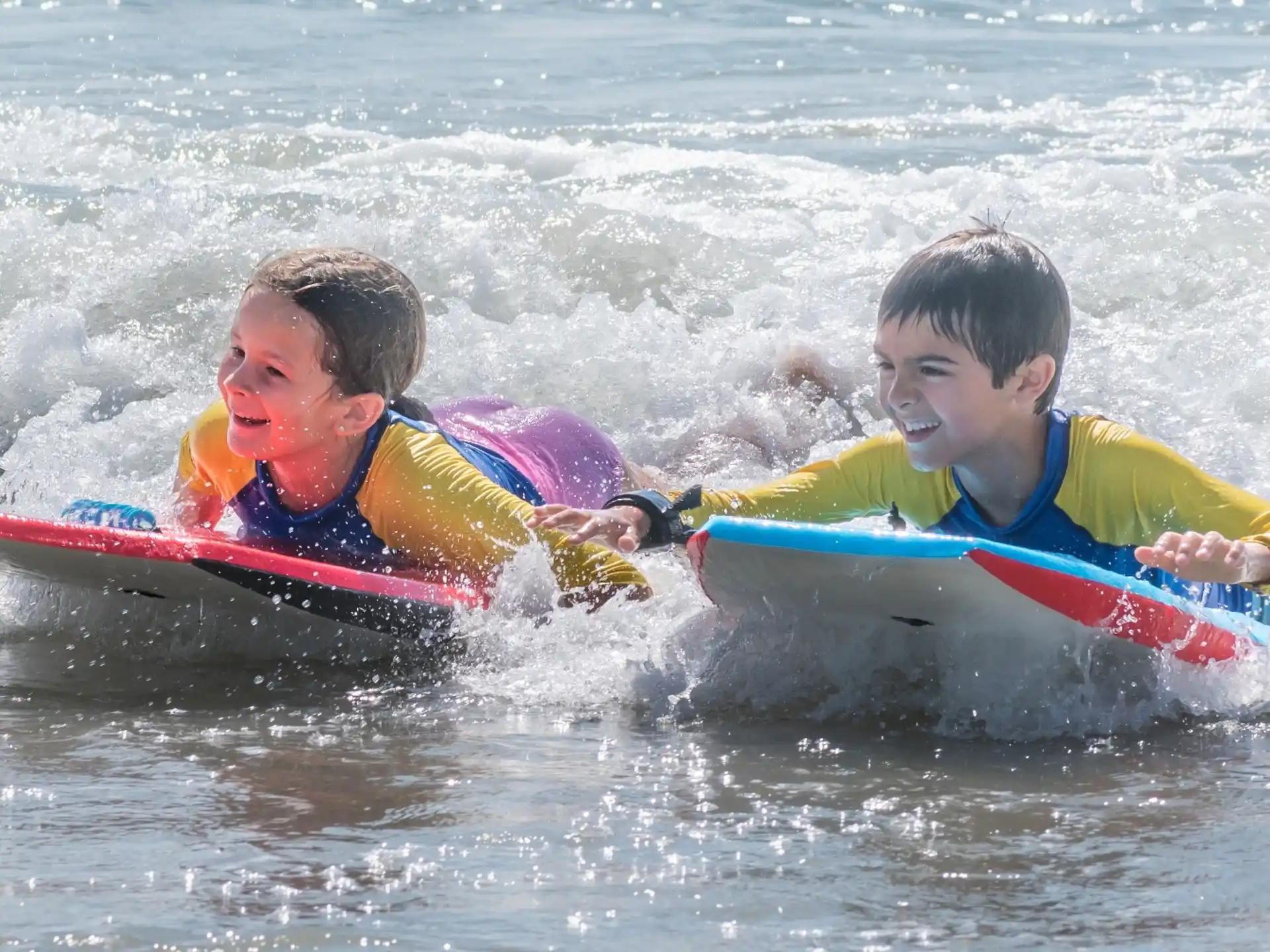 a couple of kids ride on a surfboard