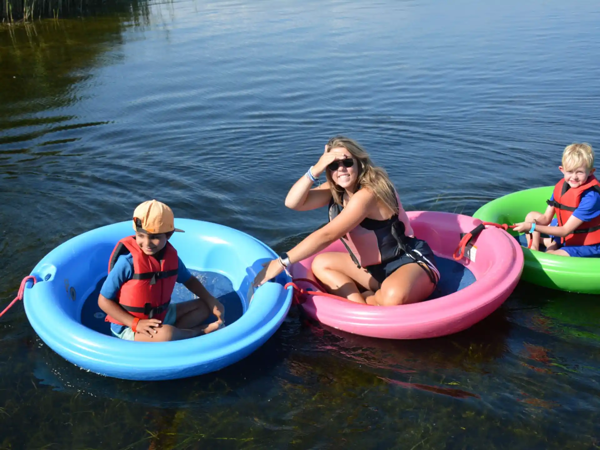 a woman and two kids in kayaks on a lake