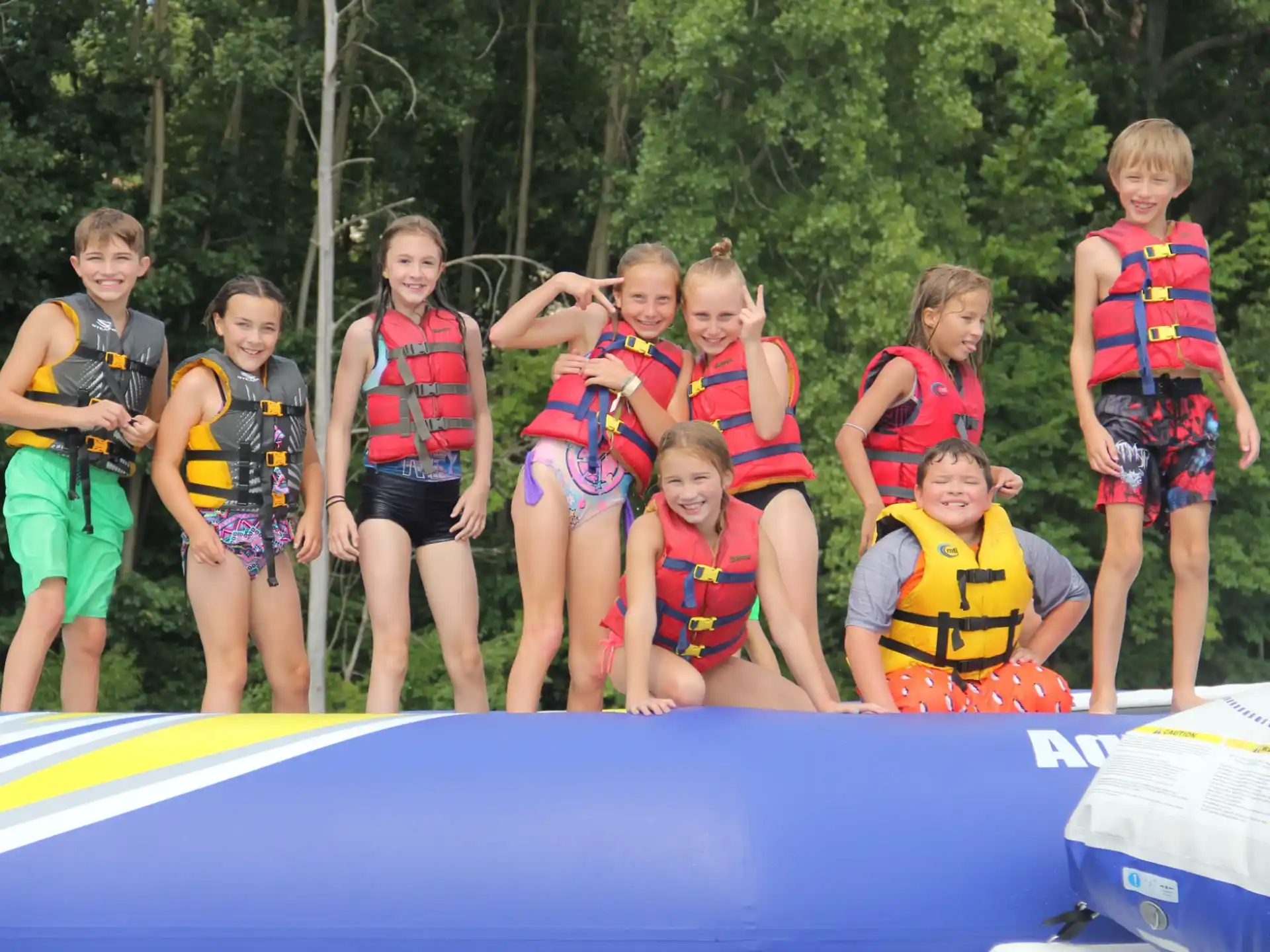 a group of kids wearing life vests and standing on a trampoline