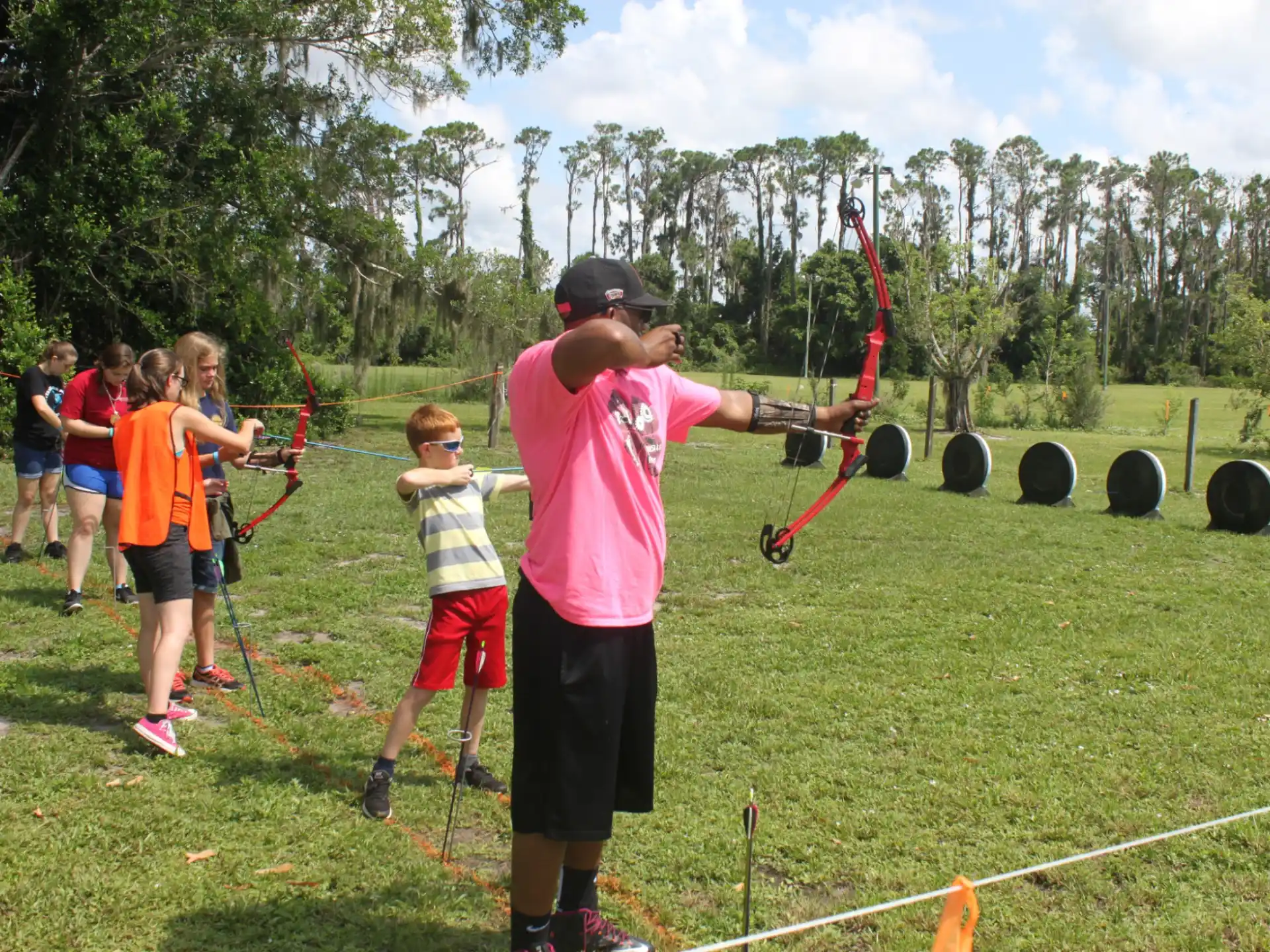 a person holding a bow and arrow with a group of people around him