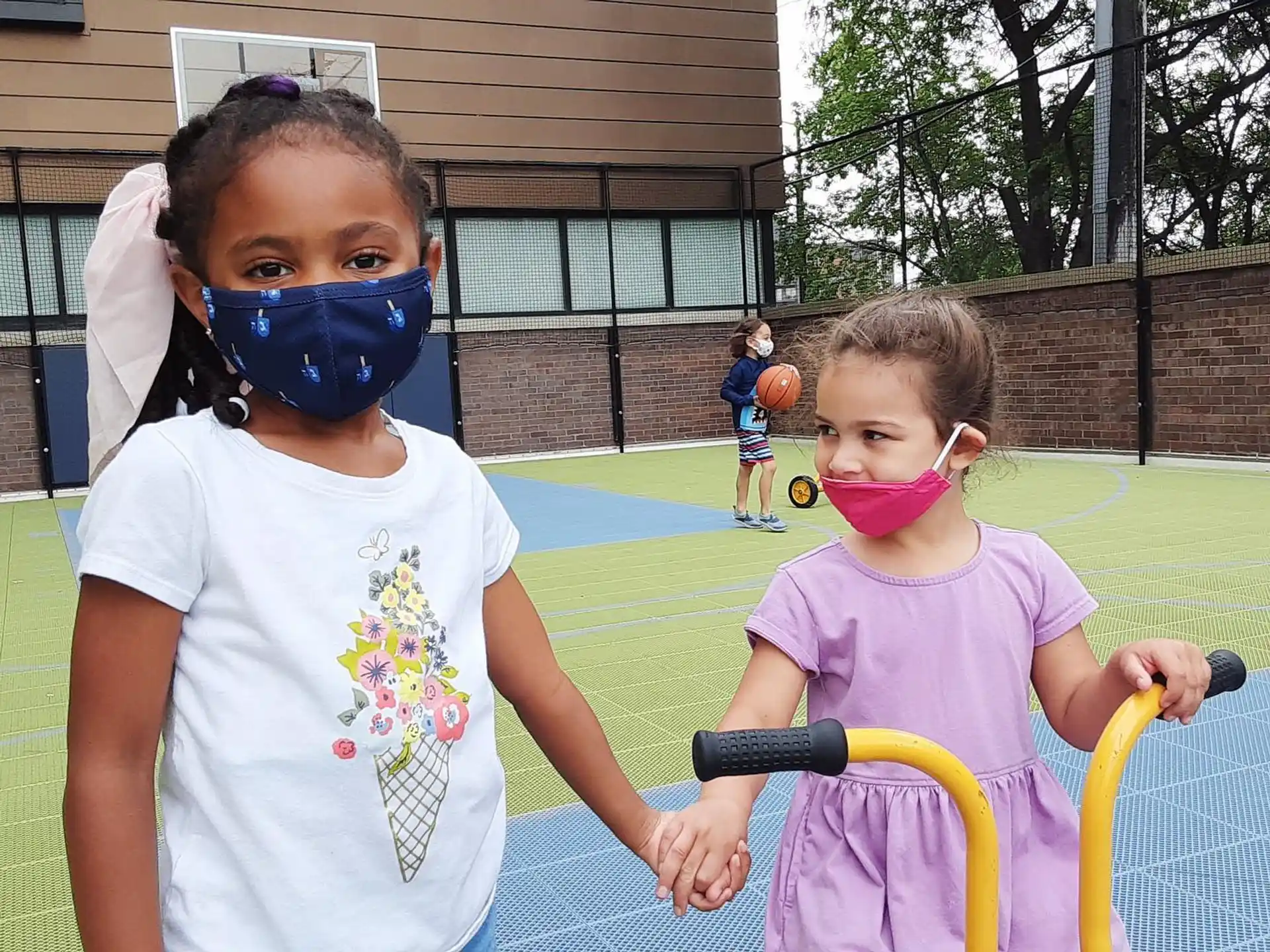 a couple of girls wearing masks and holding a bike