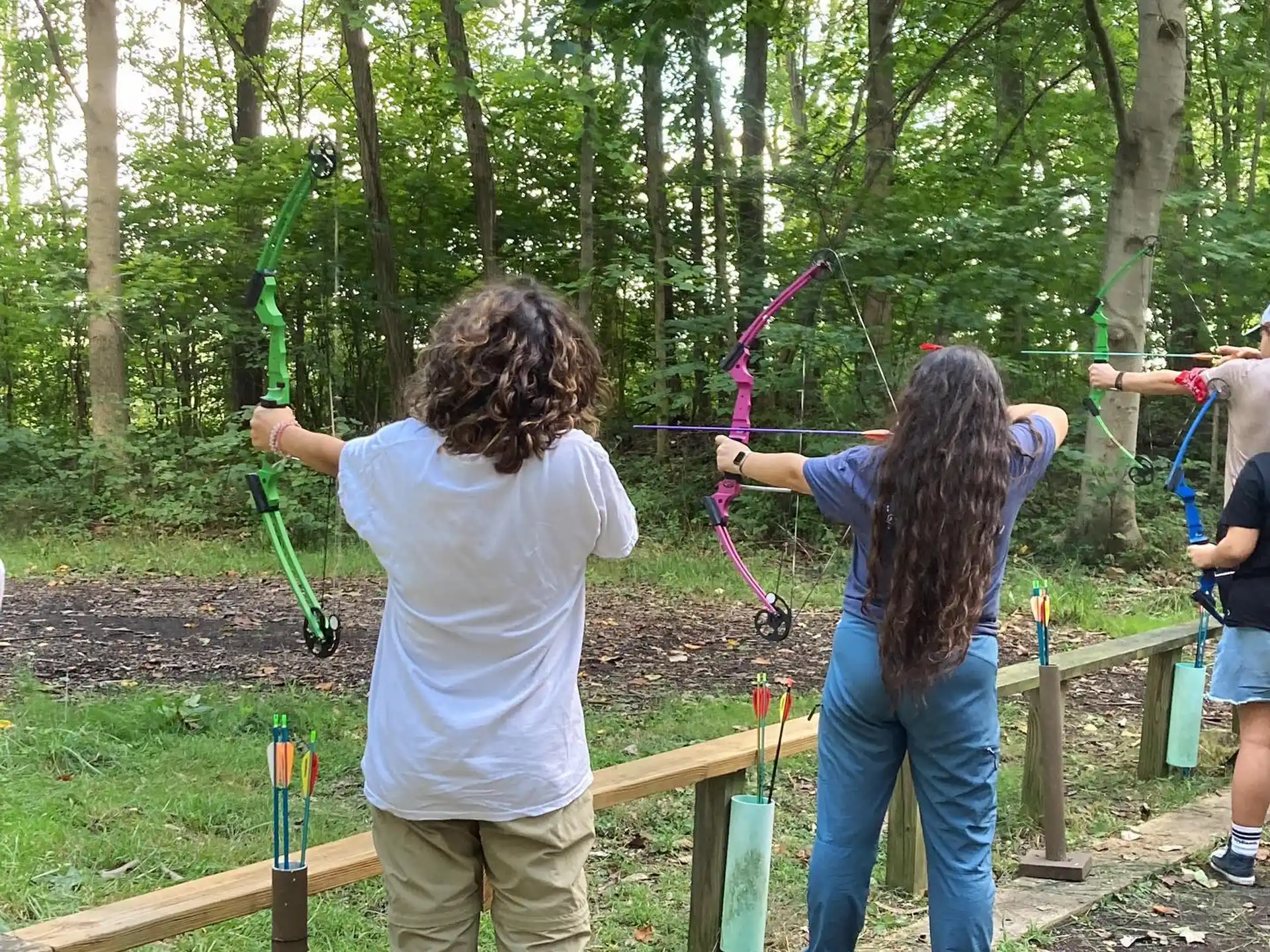 a group of kids playing with bows and arrows in a forest