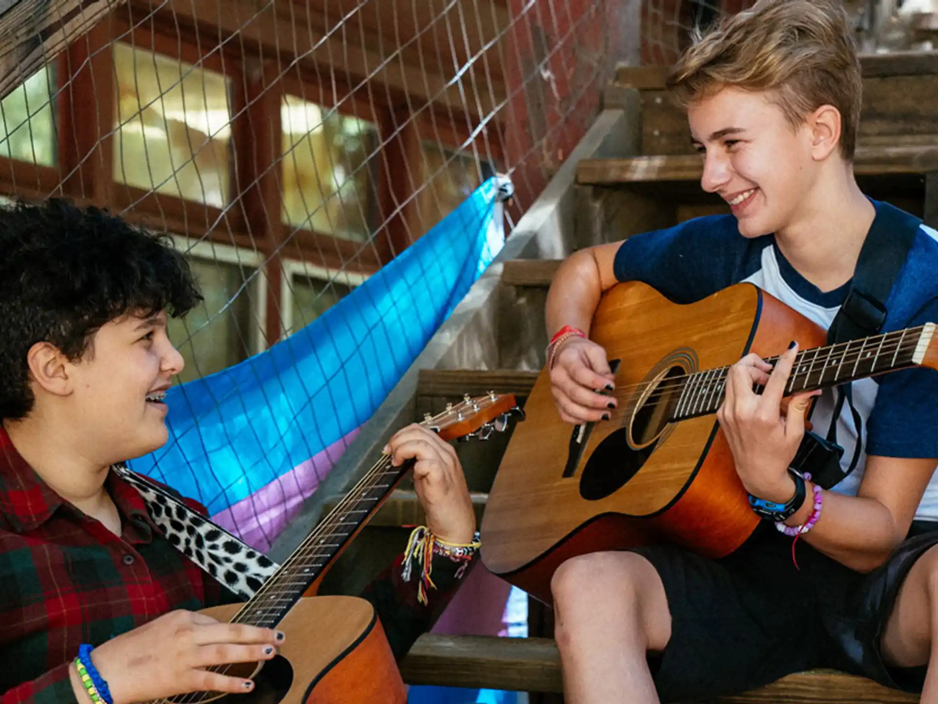 a person playing a guitar next to a person sitting on a chair