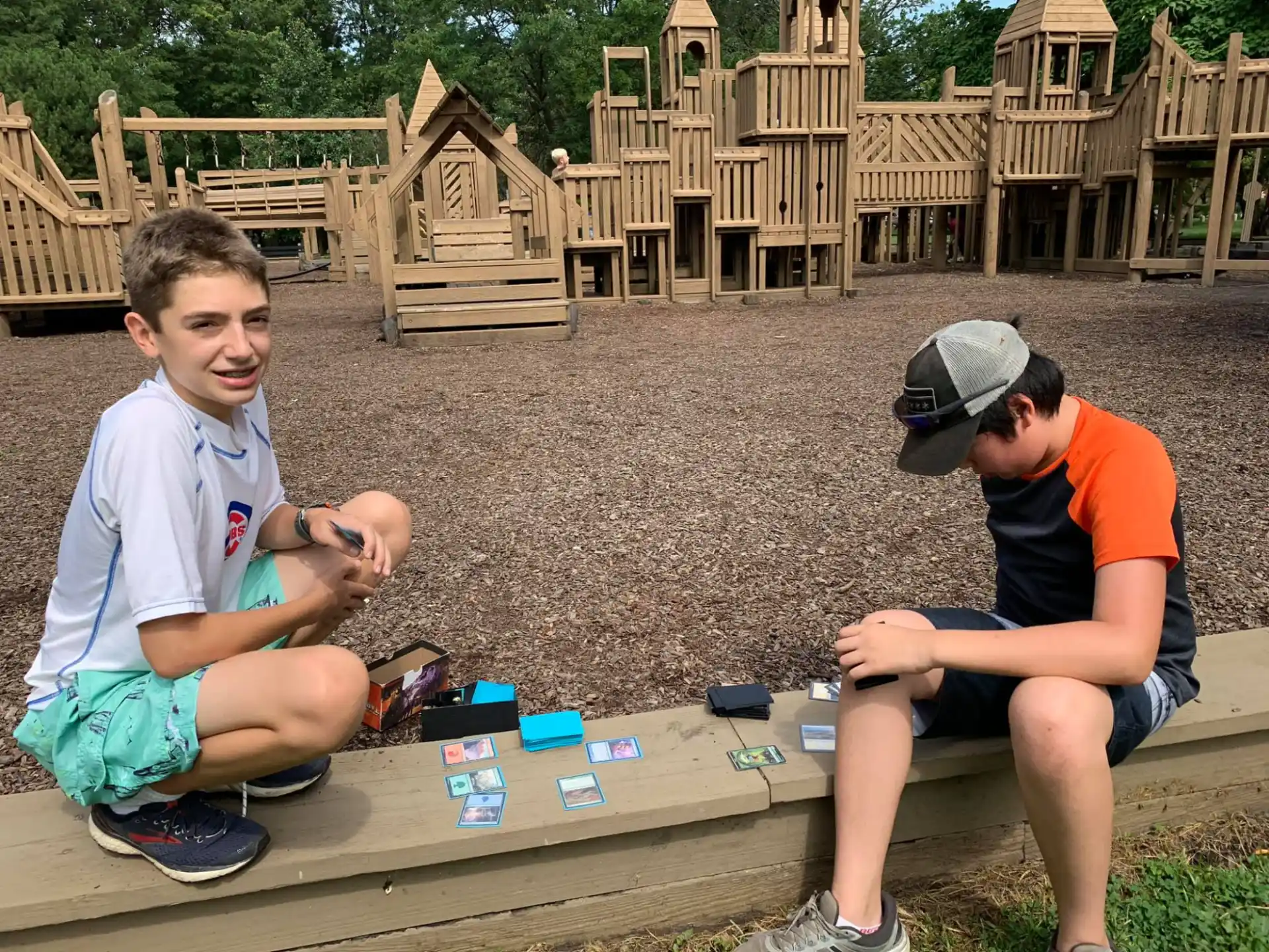 a couple of boys sitting on a bench in front of a wooden fence