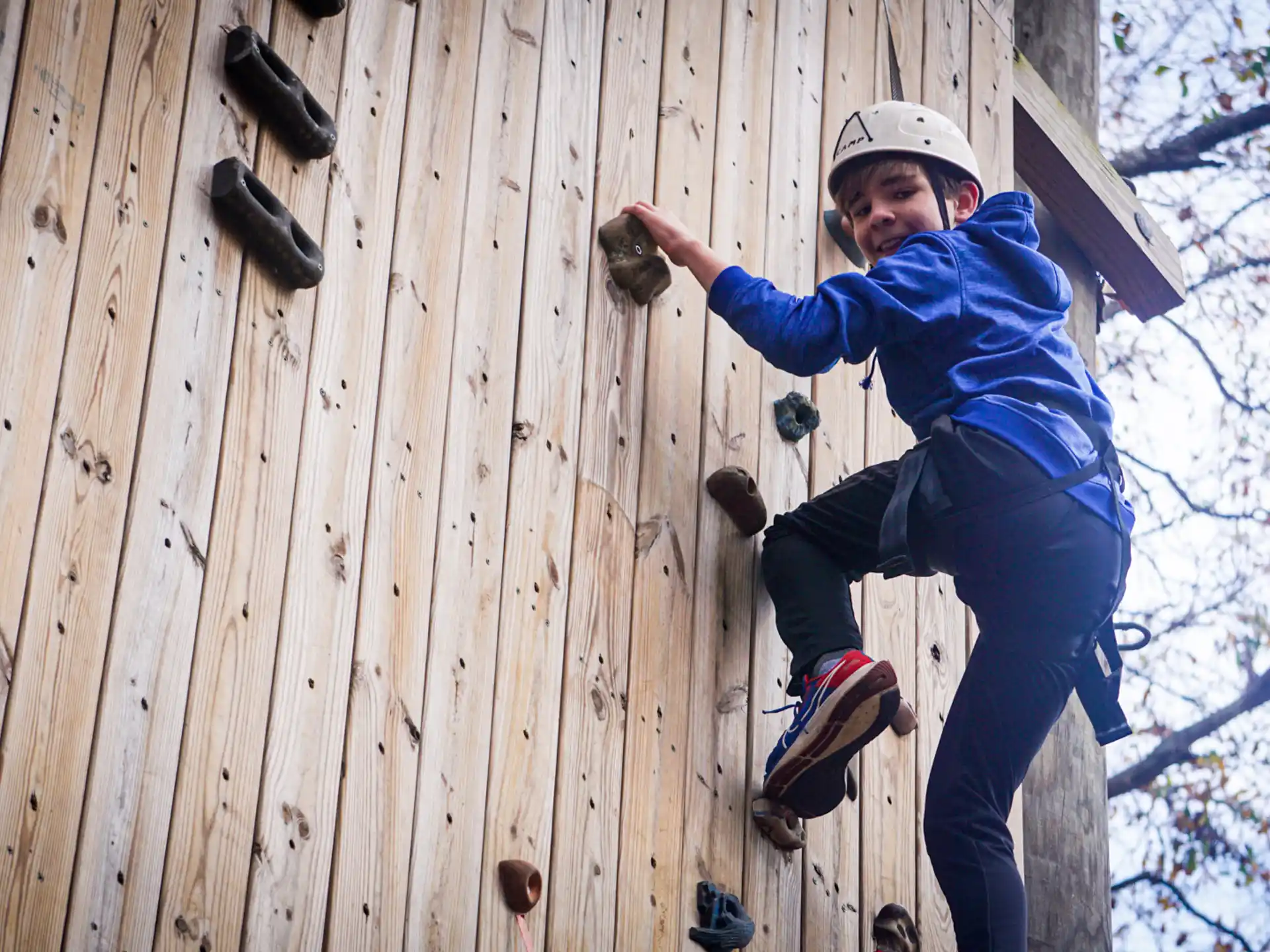 a boy climbing a wooden wall