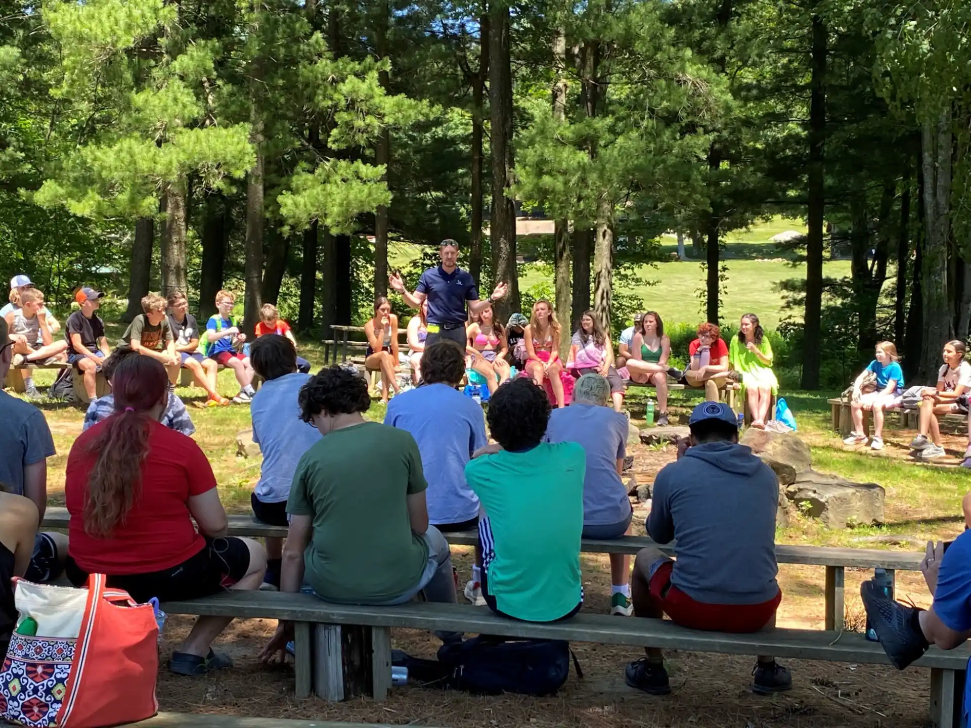 a group of people sitting on picnic tables in a park