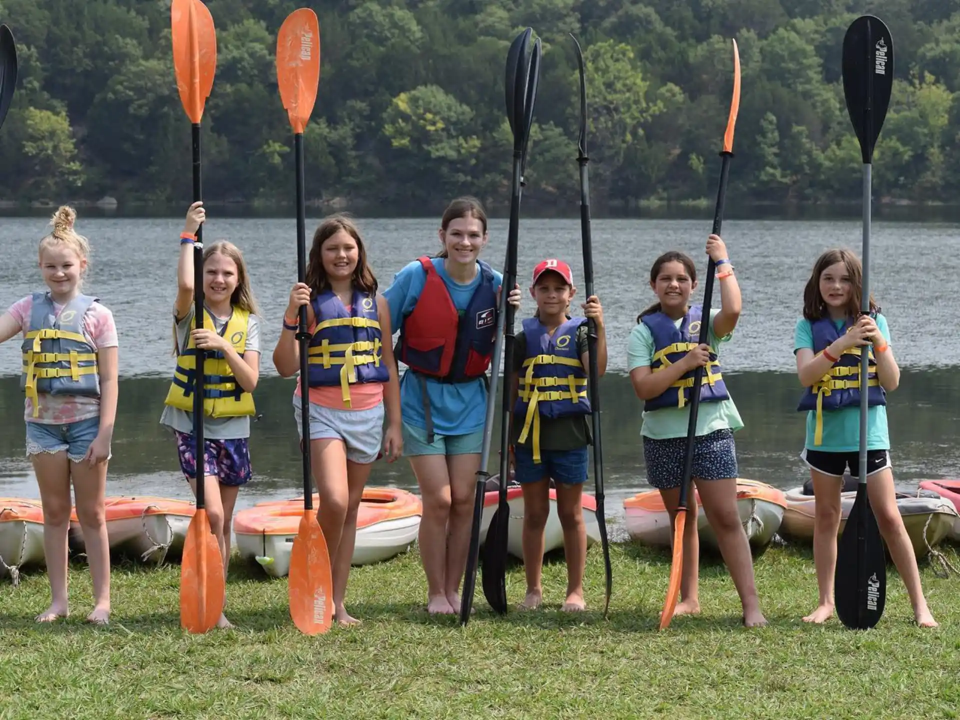 a group of people in life vests standing by a lake