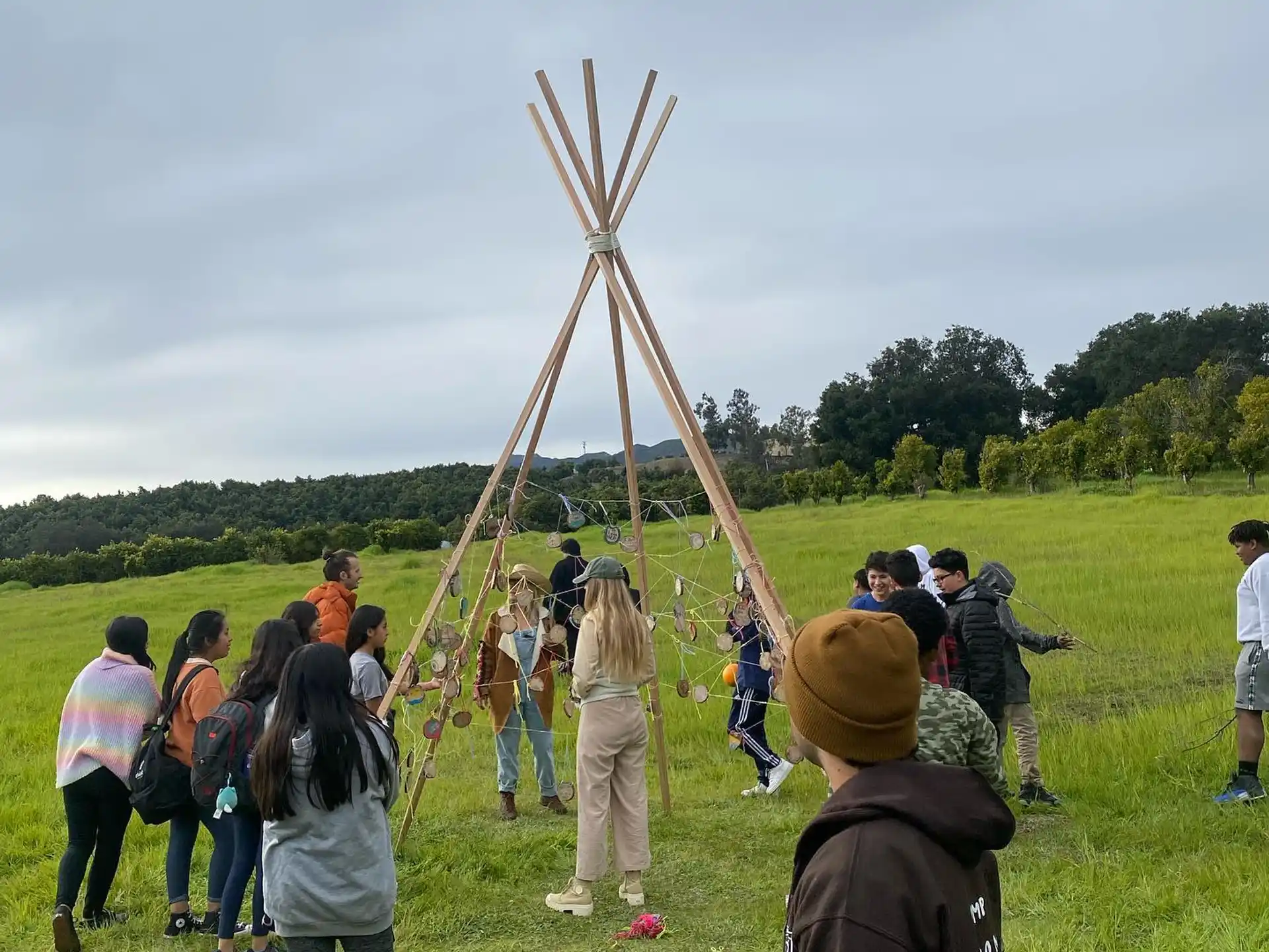a group of people standing on a grass field with a large wooden cross
