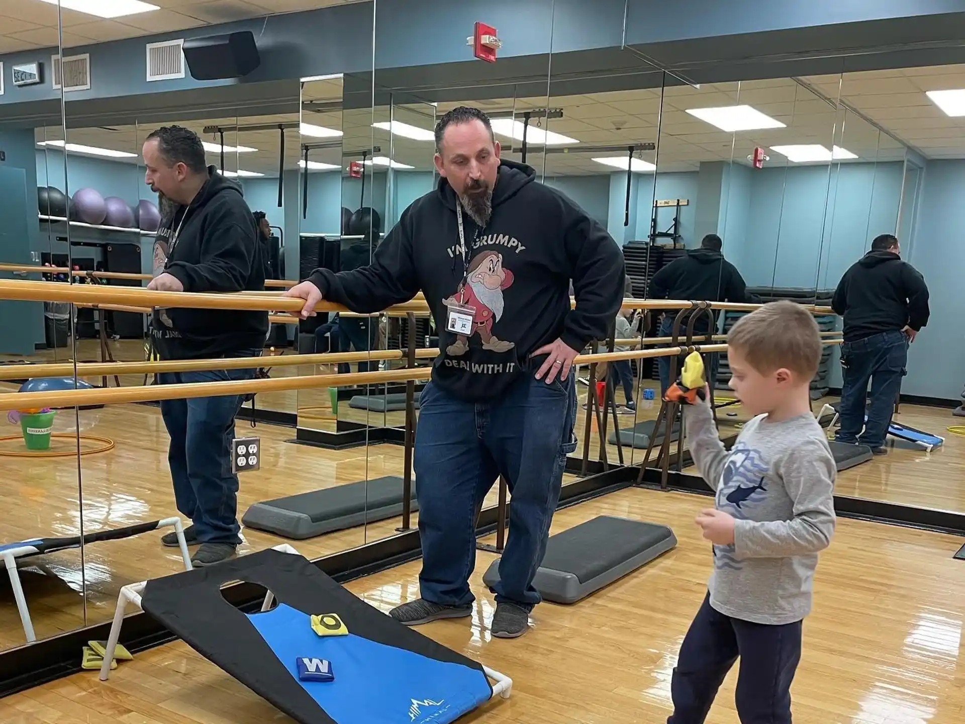 a person and a boy holding a large sword in a room with other people